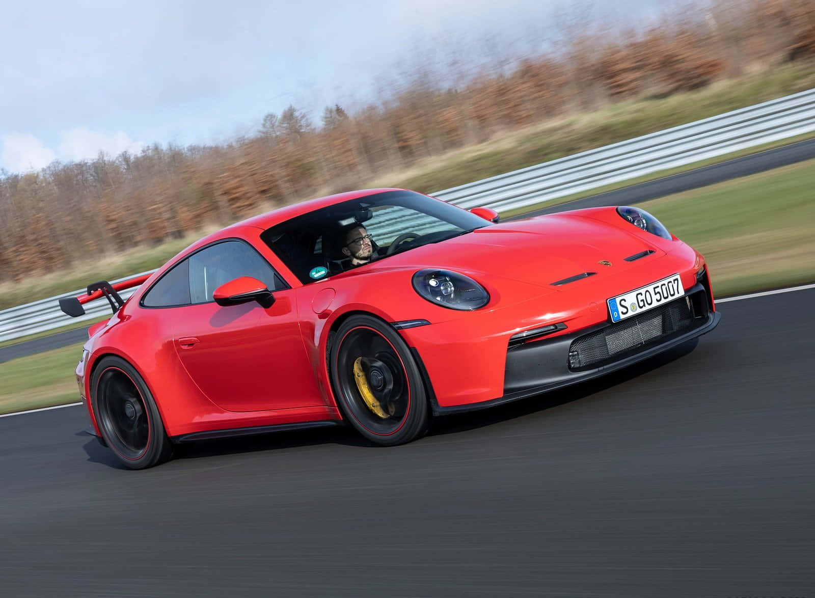 紅色保時捷911 GT3 RS在賽道上奔馳，伴有秋葉。
