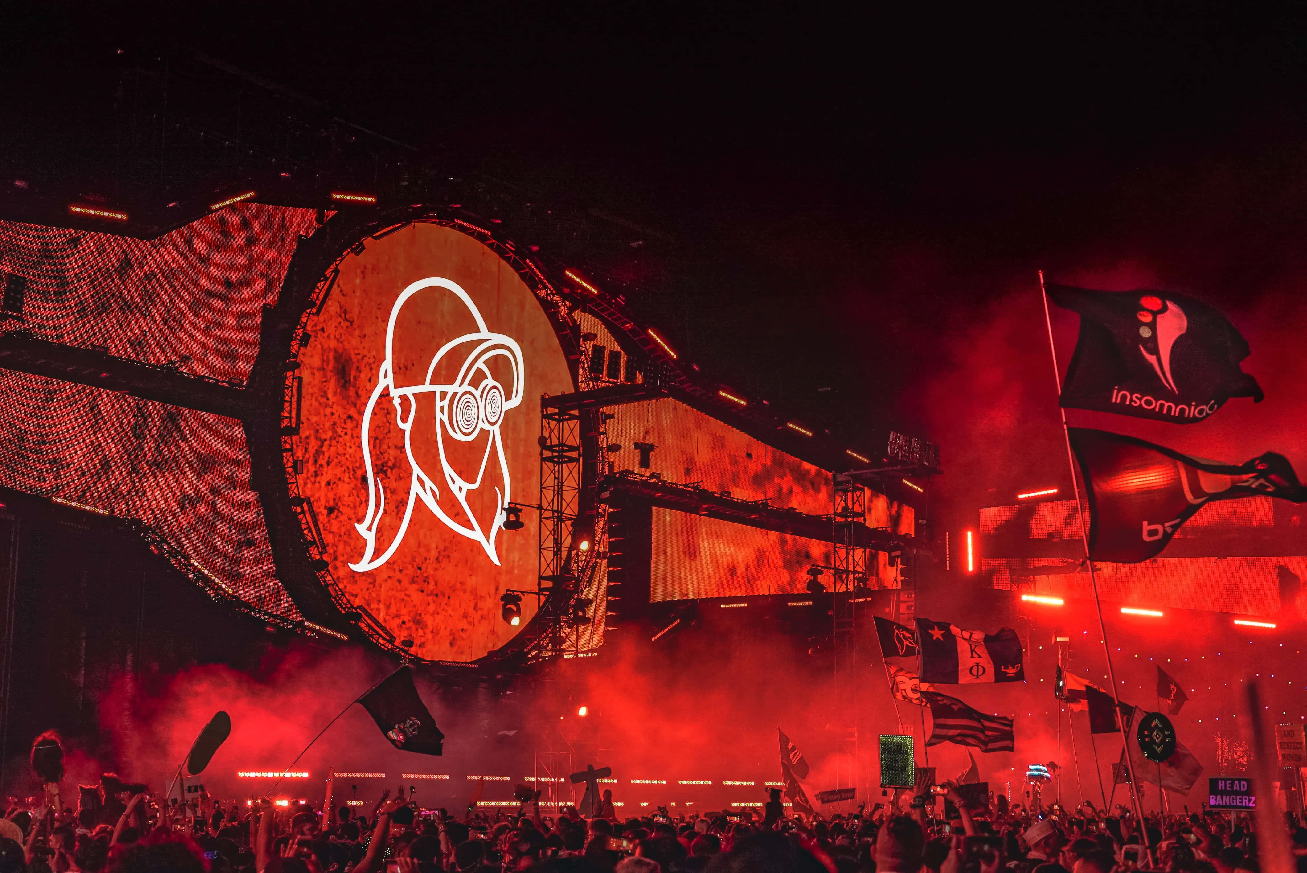 music festival 桌布 壁紙 — 夜間電子音樂節上，大量人群沐浴在紅色煙霧和閃爍的舞台燈光中。