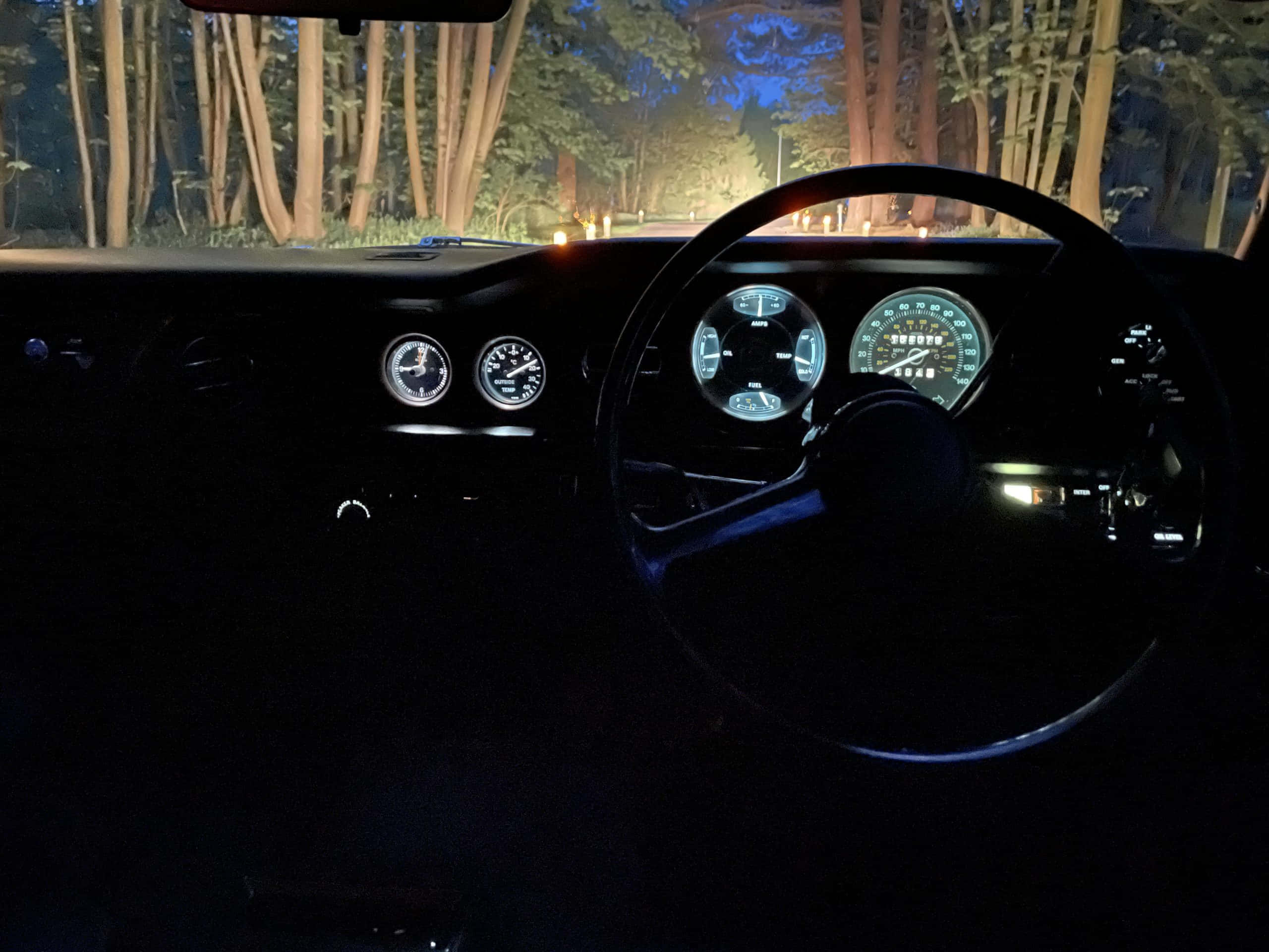 Bentley T2 桌布 壁紙 — 夜間駕車穿過森林，儀表板燈光在復古車的黑暗車廂內閃爍。