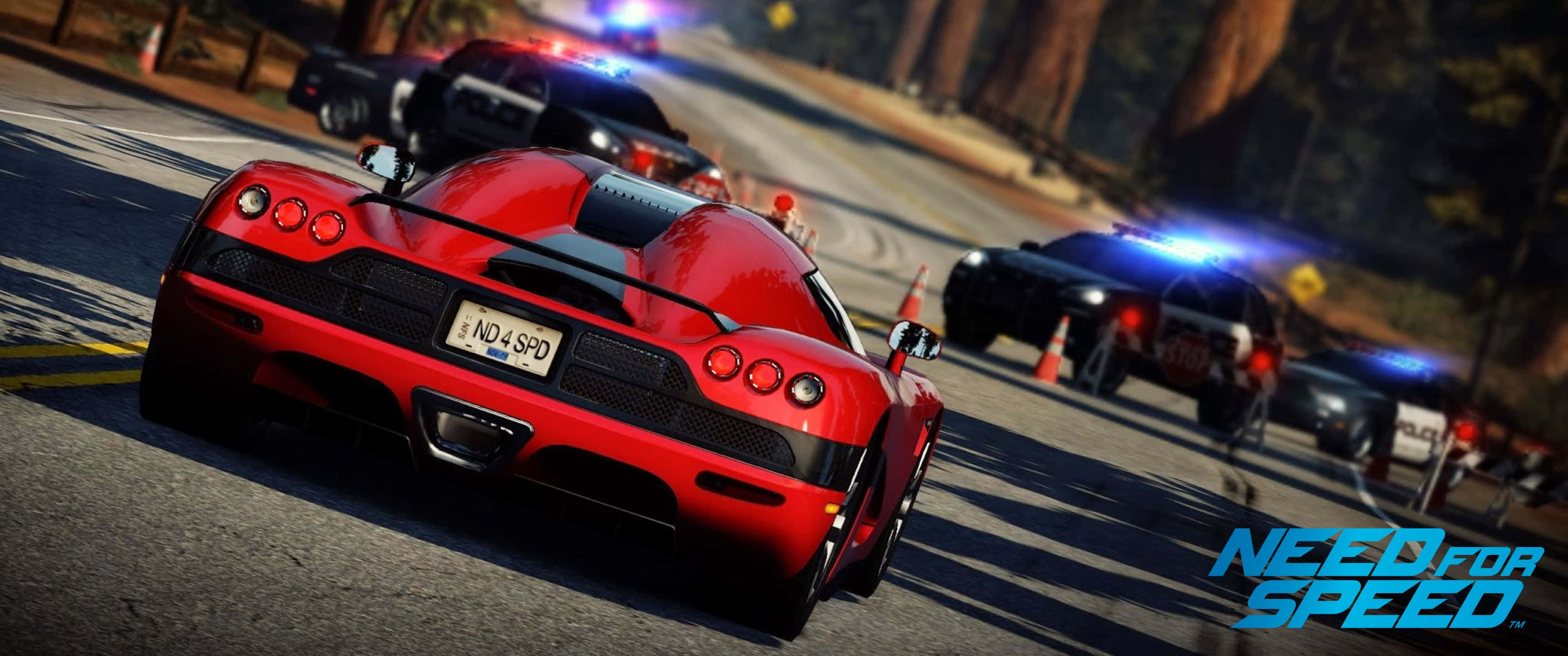 夜間駕馭《Need For Speed》 壁紙 — 在電子遊戲場景中，一輛紅色跑車在森林道路上飛馳，被閃著警燈的警車追趕。
