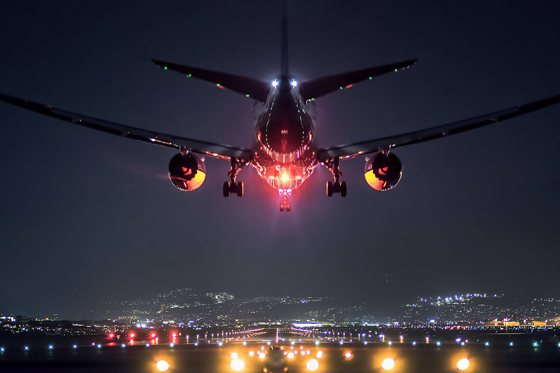 夜間降落的飛機，背景是城市燈光。