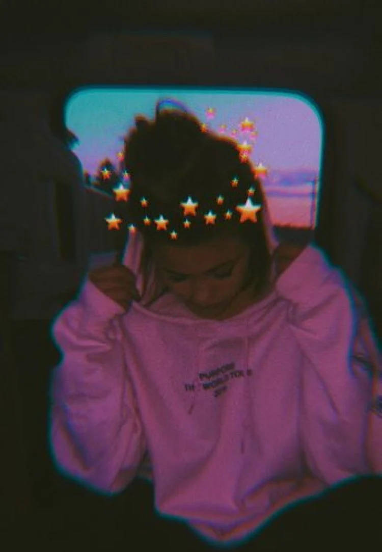 穿著粉紅色連帽衫的人，黃昏時在車內頭上有發光星星。