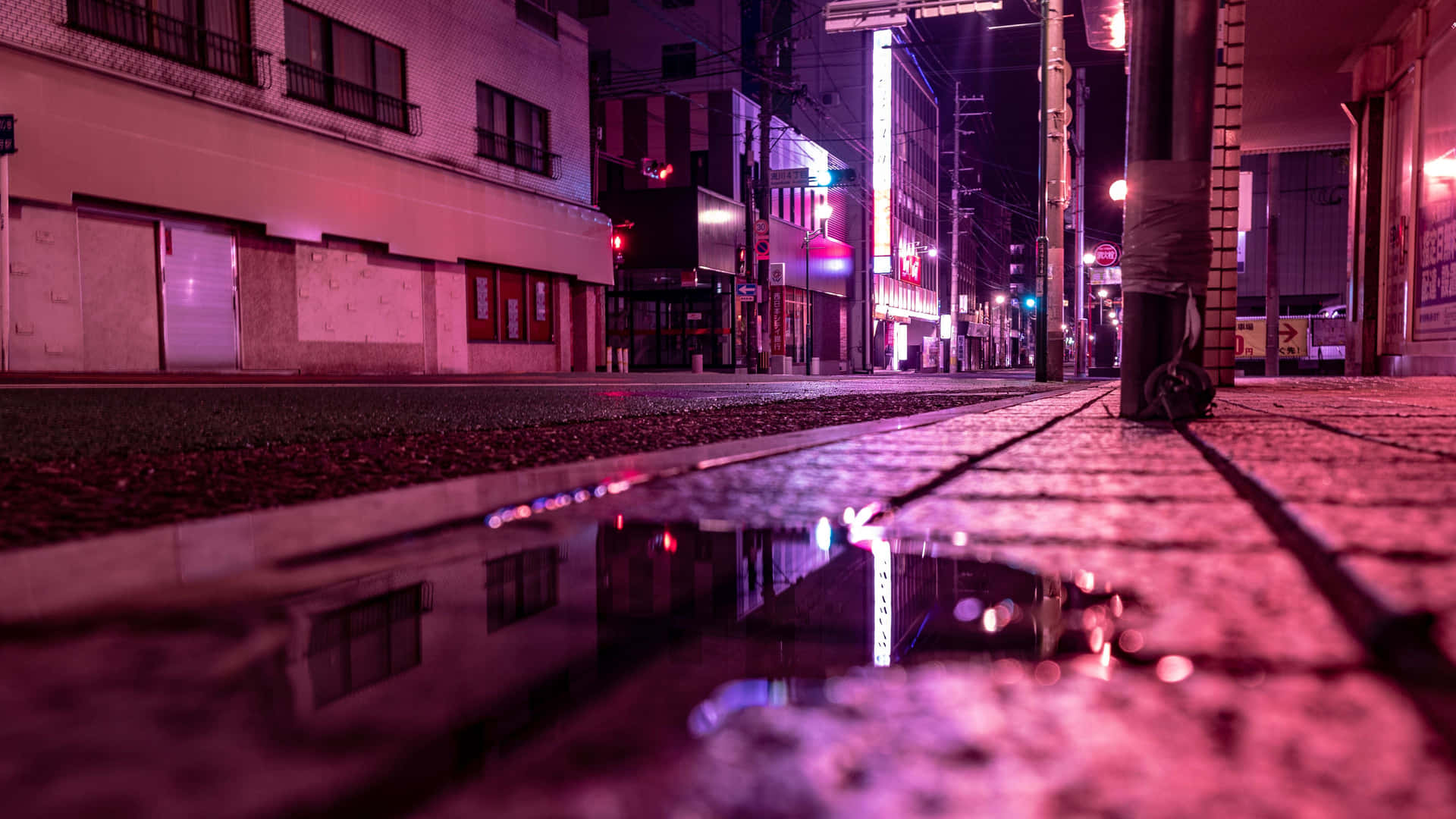 霓虹燈光在夜晚濕漉漉的城市街道水坑中反射。