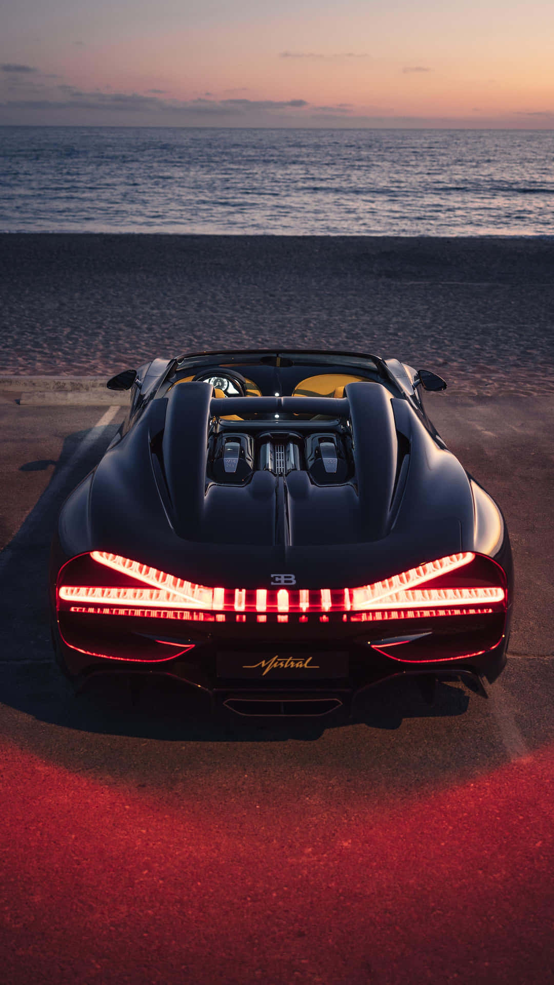 日落時分沙灘上帶紅燈的黑色Bugatti跑車。