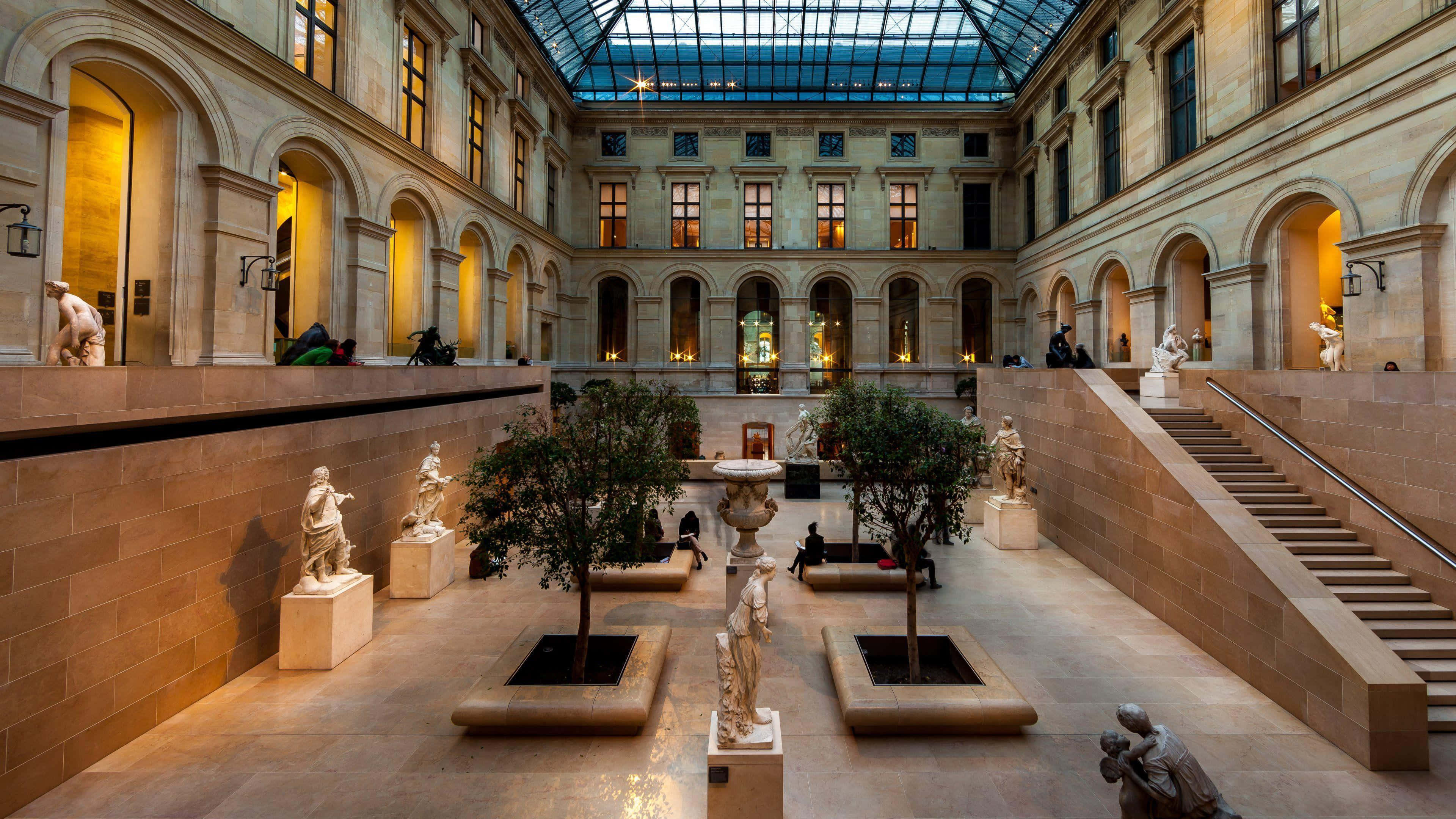 Museums 桌布 壁紙 — 大型博物館庭院，內有古典雕像、樹木和拱形窗戶，上方是玻璃天花板。