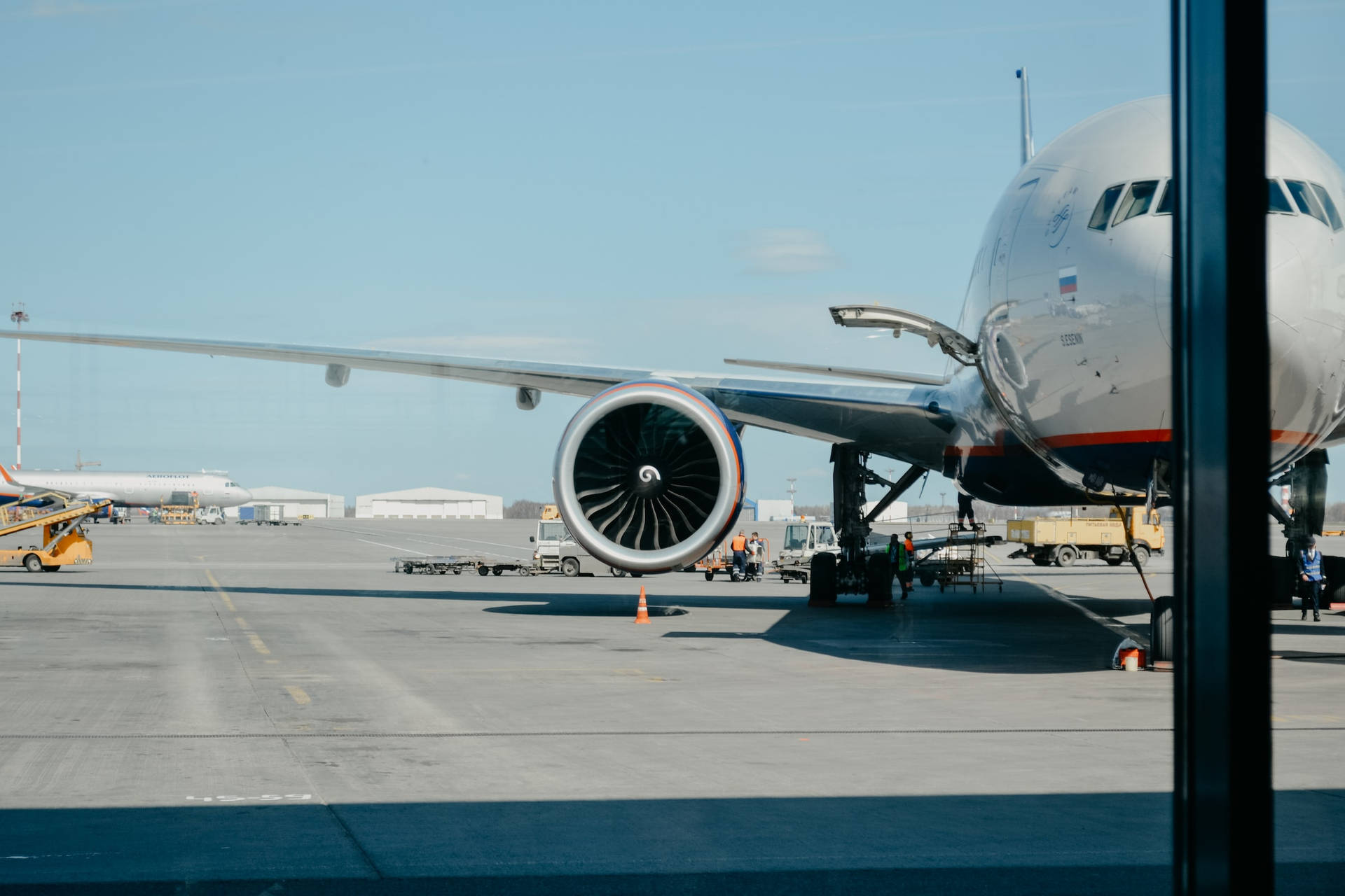 一架大型飛機停在機場停機坪，地勤人員和設備清晰可見。