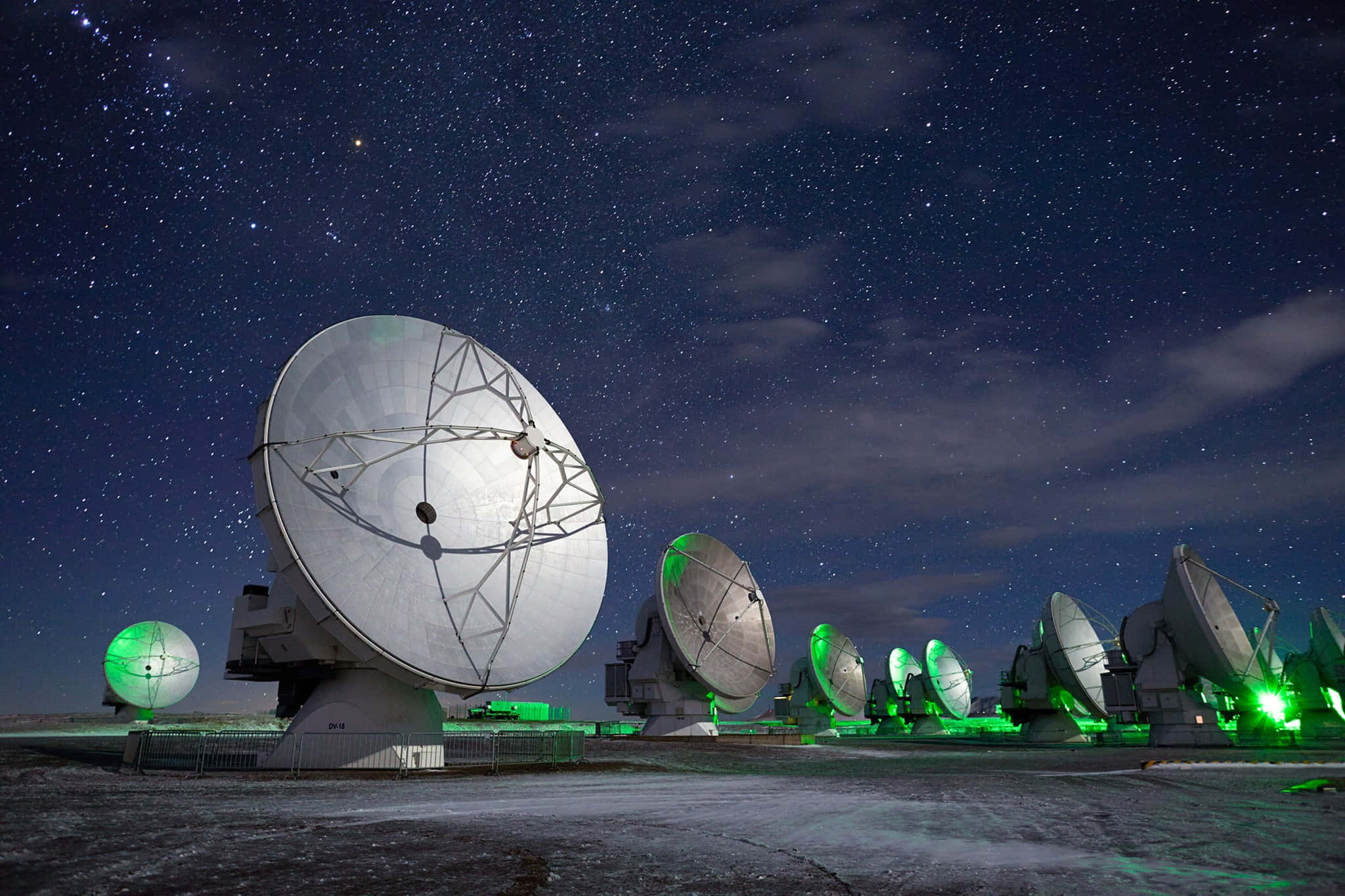 Radio Telescope 桌布 壁紙 — 大型射電望遠鏡在偏遠的沙漠景觀中，於繁星點點的夜空下發出綠色光芒。