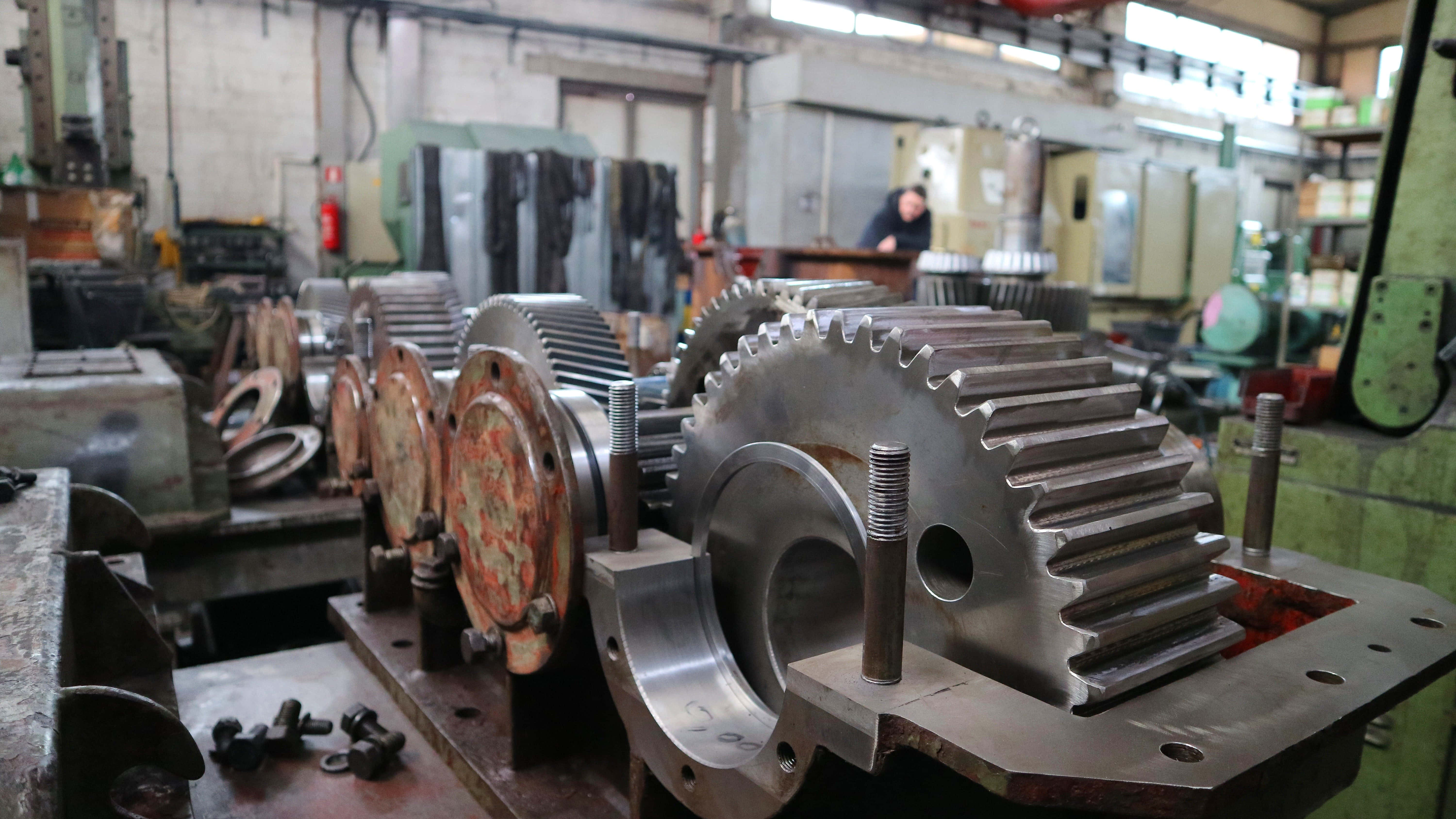 Machine 桌布 壁紙 — 大型工業齒輪和機械零件排列在雜亂工廠車間的工作台上。