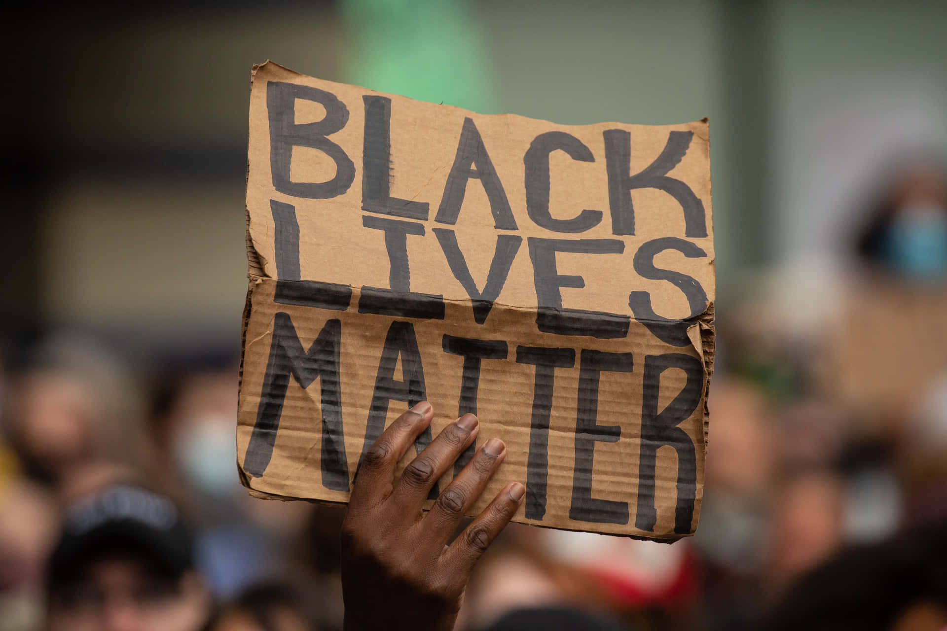 在人群中手持「Black Lives Matter」抗議標語的手。