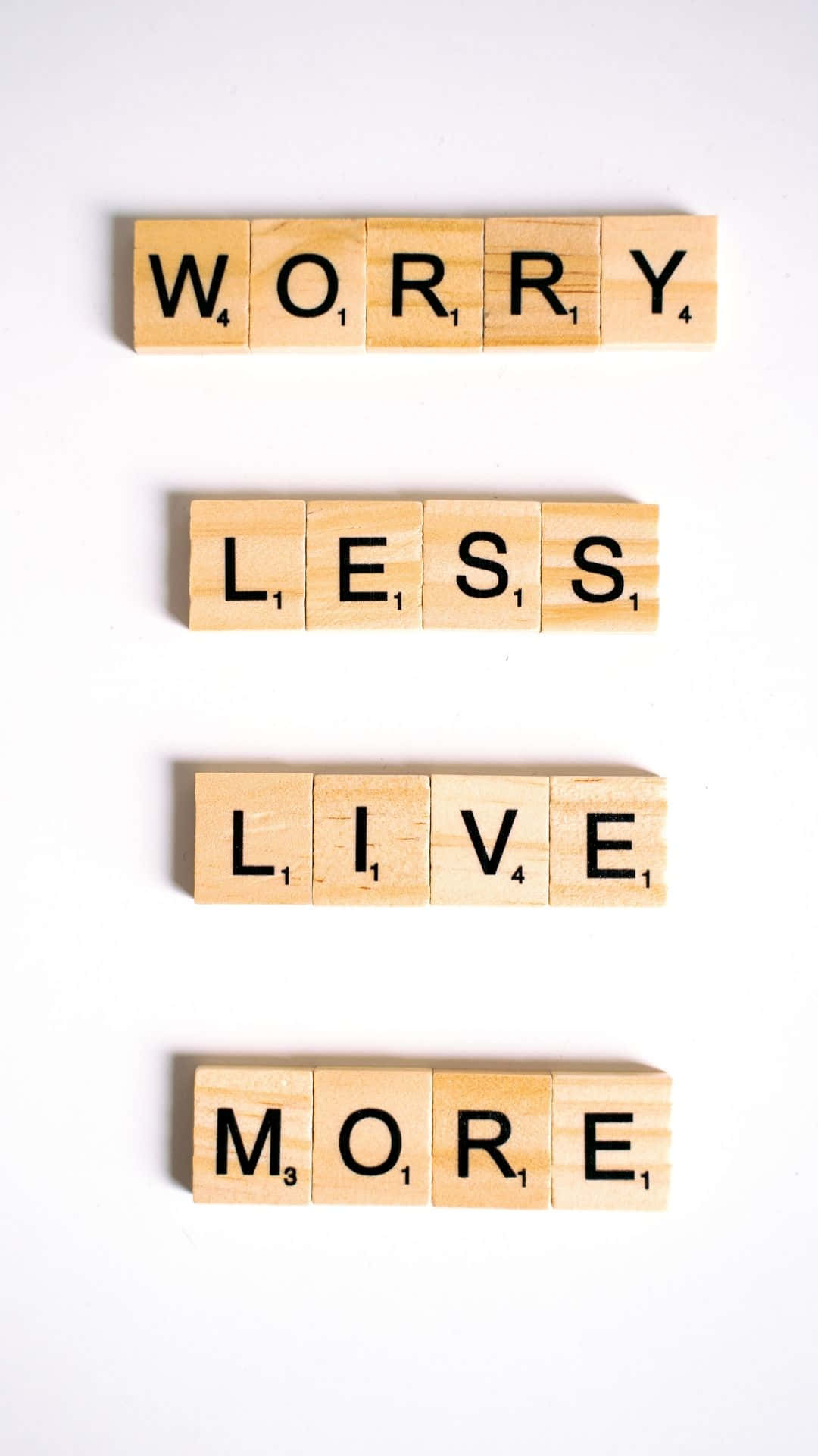 木製 Scrabble 字母塊排列成在白色背景上讀出 'Worry Less Live More'。
