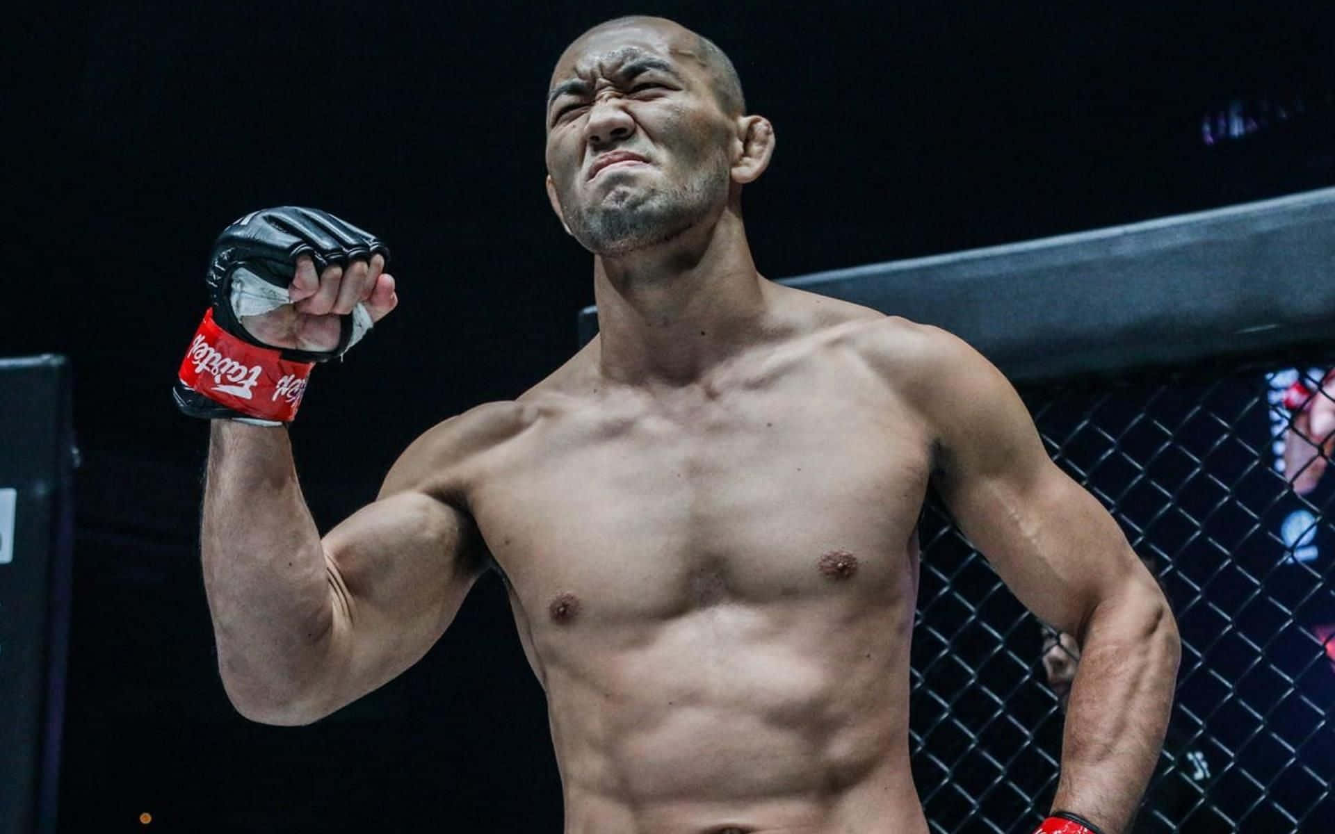 一位勝利的MMA拳手在八角籠內高舉拳頭。