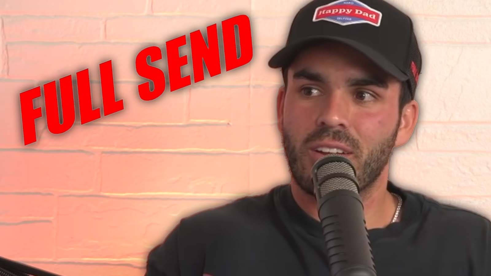 戴帽子的男人對著咪高峰說話，磚牆上有「FULL SEND」文字。