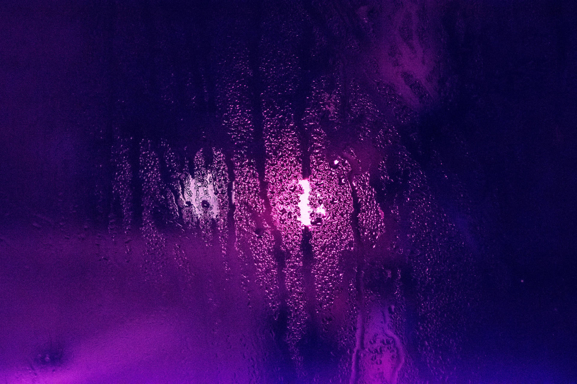 紫色和粉紅色的霓虹燈光穿過被雨水打濕的窗玻璃。