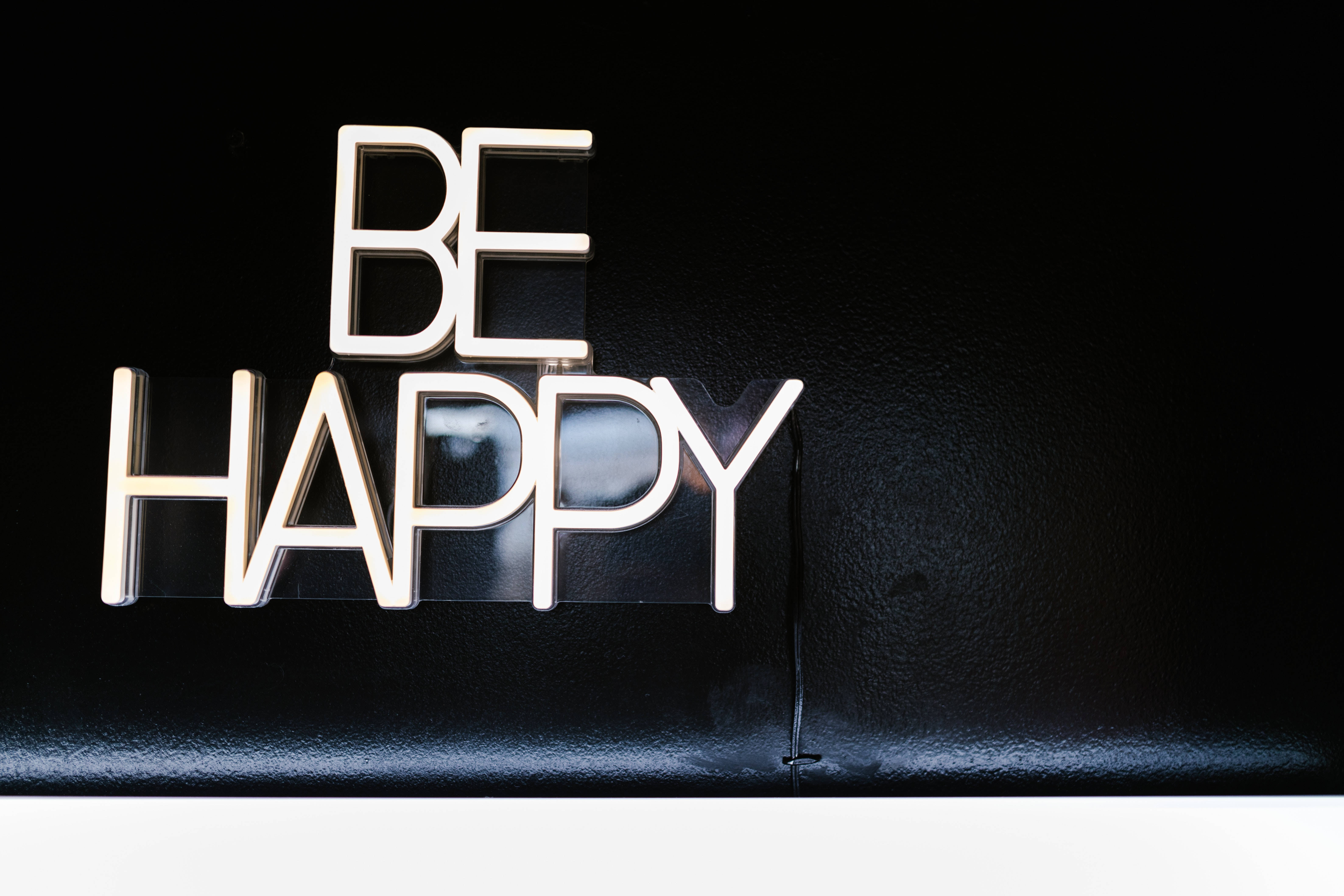 開心 桌布 壁紙 — 大膽的白色3D字母拼出「BE HAPPY」，在帶有柔和光線的紋理黑色背景上脫穎而出。