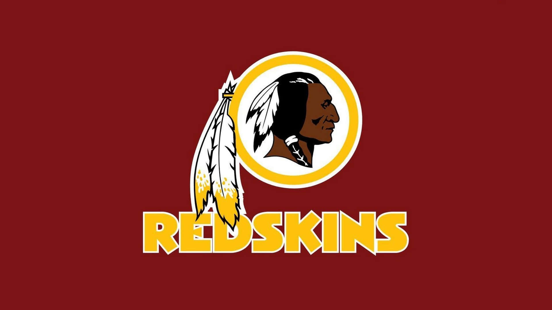 Washington Football 桌布 壁紙 — 大膽的紅色背景上有一個黃色輪廓的圓形標誌，上面有美洲原住民側面和羽毛，下方以粗體黃色字母顯示「REDSKINS」字樣。