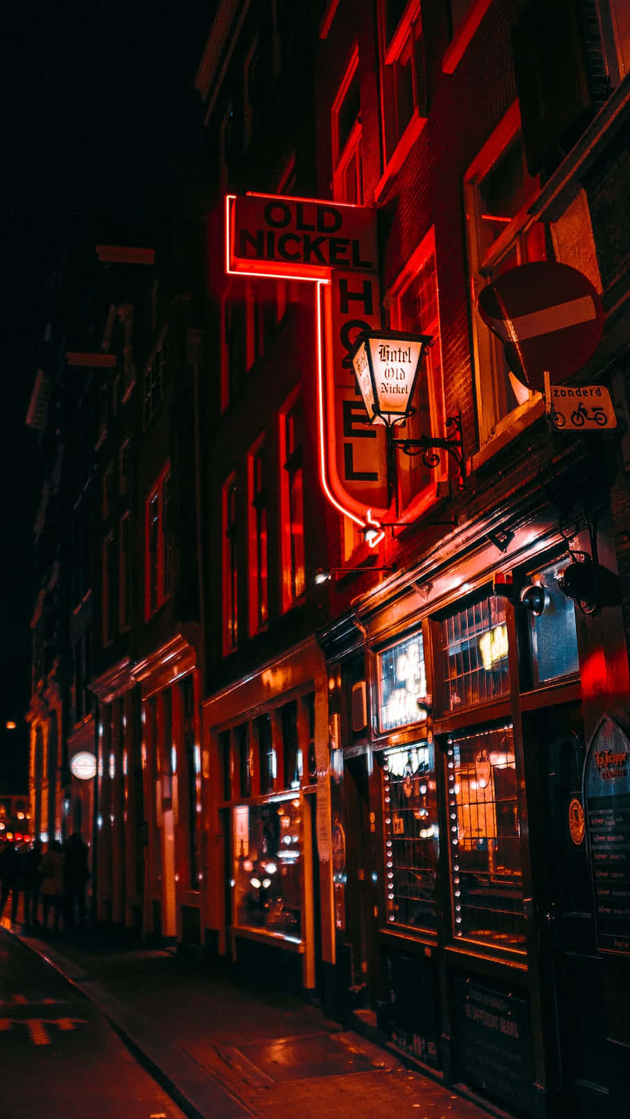 紅色霓虹燈酒店招牌照亮了夜晚潮濕的城市街道。