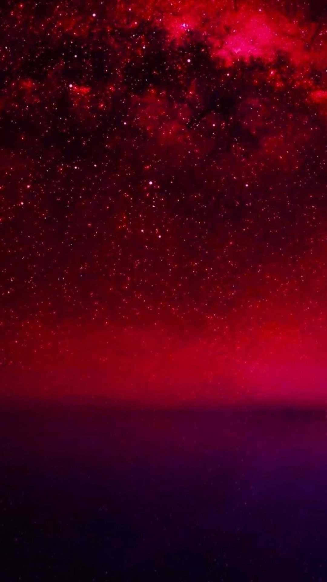 紅色和紫色的宇宙天空，星星和星雲在黑暗的地平線之上。