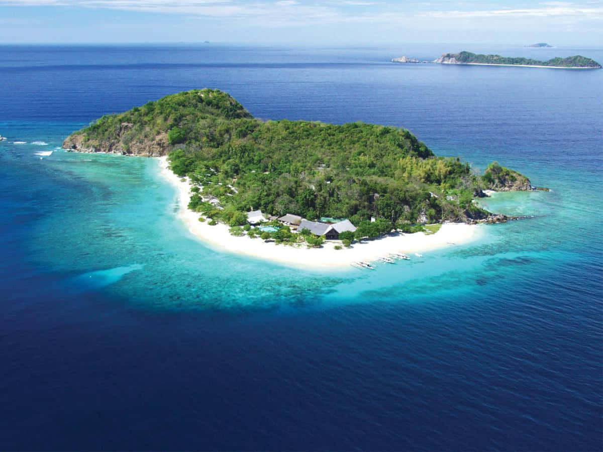 熱帶島嶼度假村，擁有白色沙灘和碧綠海水，四周環繞著深藍色海洋。