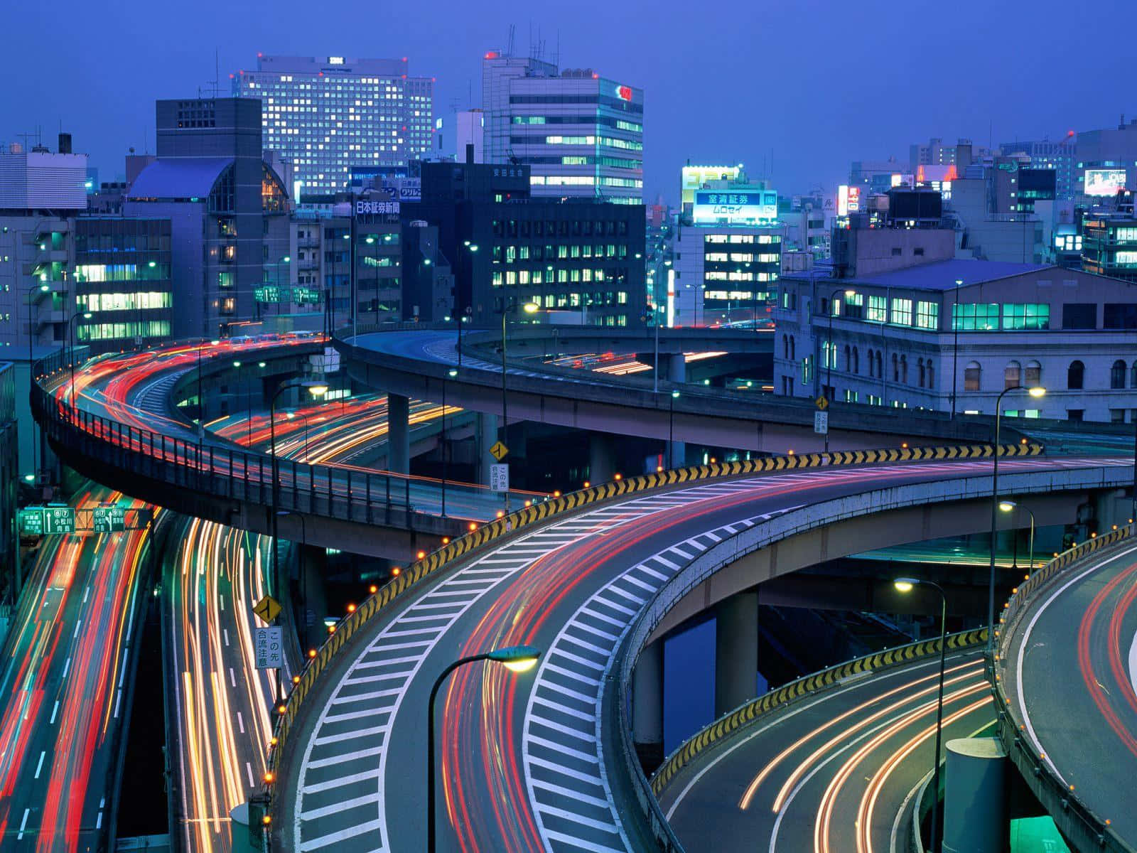 黃昏時分彎曲的高速公路，移動的汽車留下光跡，建築物閃閃發光。