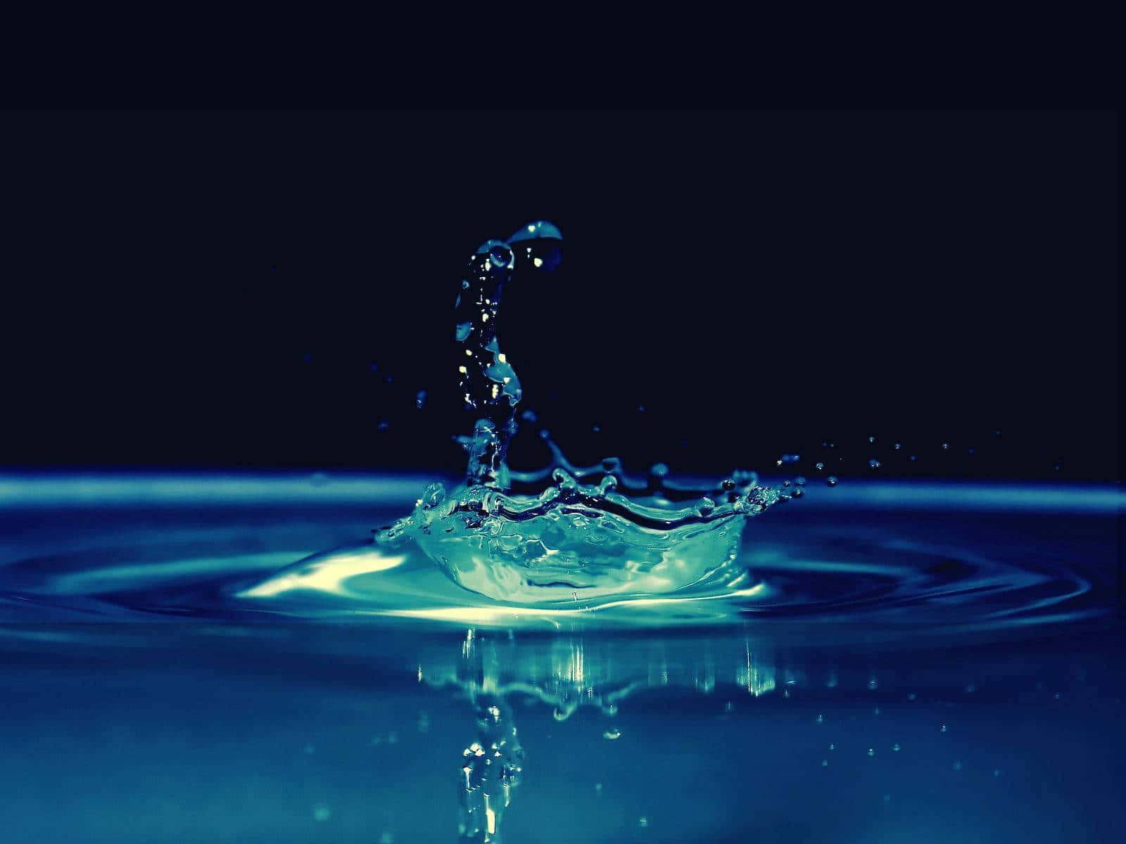 一滴水珠濺入水中，在藍光下形成水珠和漣漪的皇冠。
