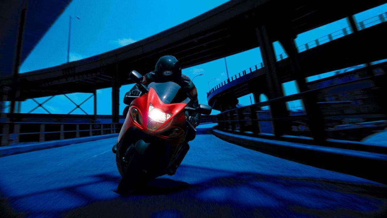 紅色電單車在天橋下傾斜入彎，黃昏時分。