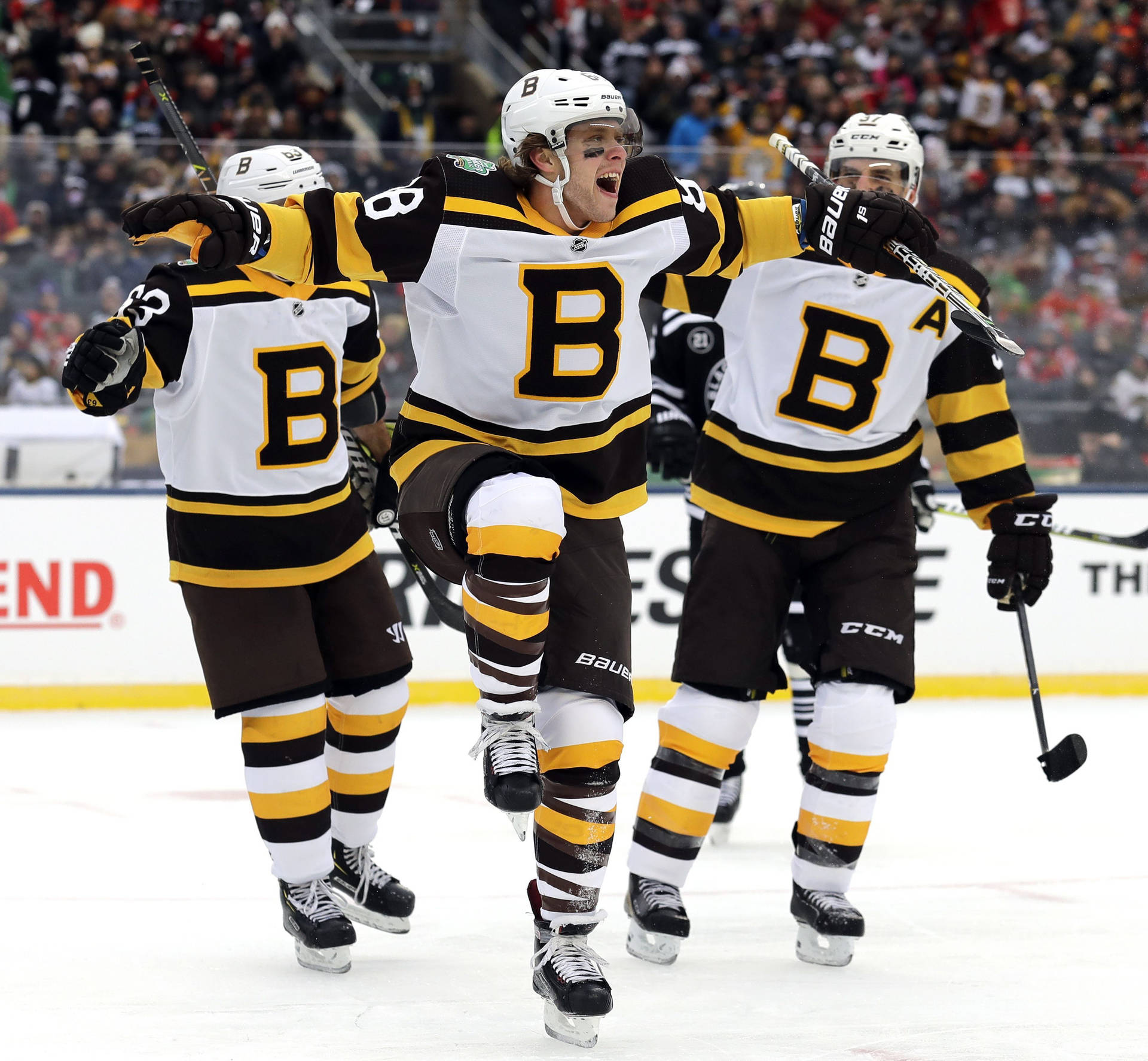 大衛·帕斯特納克慶祝NHL冬季經典賽進球 壁紙 — 三名身穿黑色和金色球衣的冰球運動員在冰上高舉雙臂，帶著喜悅的表情慶祝入球。