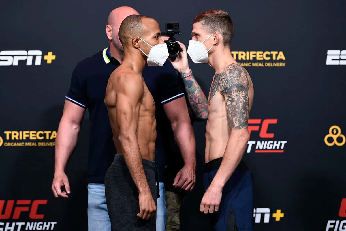 兩名戴著口罩的UFC拳手在稱重活動中面對面站立。