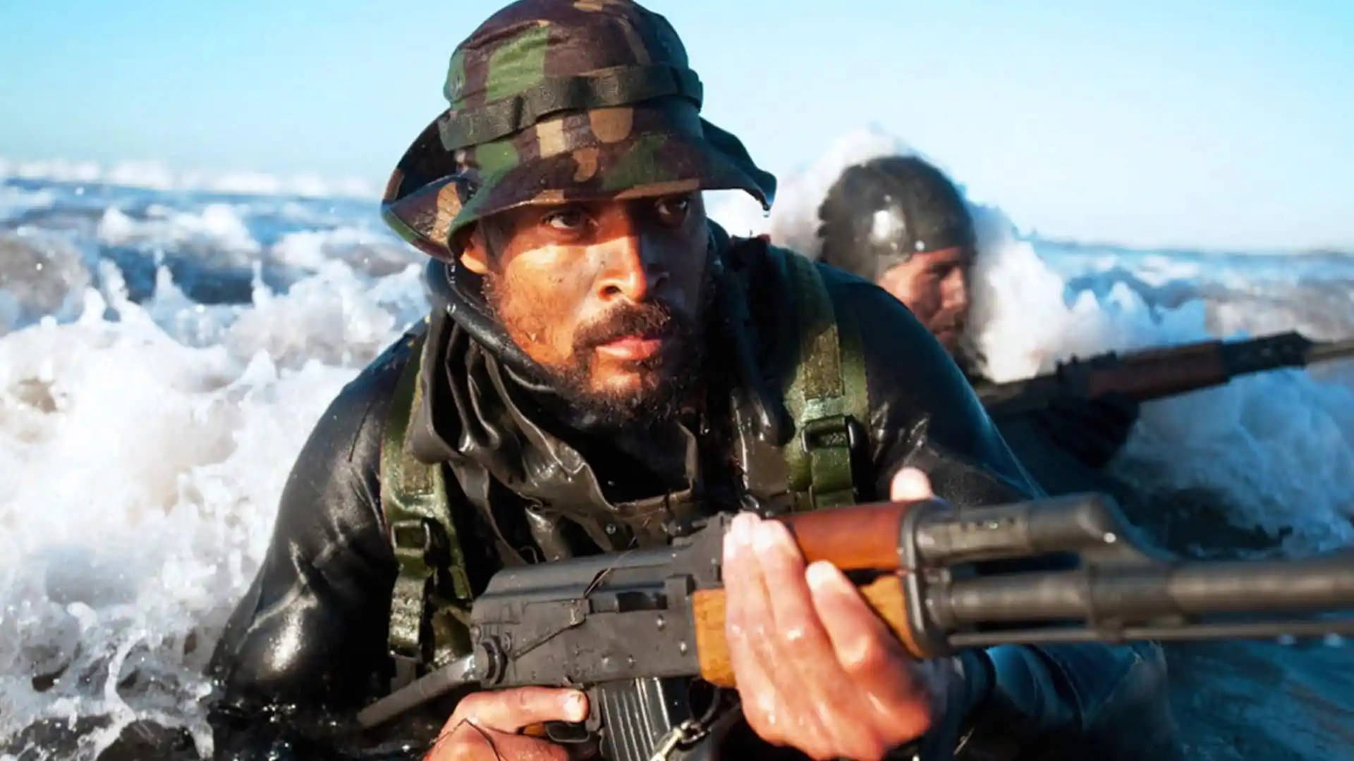 身穿迷彩裝備的士兵在冰冷的水中手持步槍涉水而行。