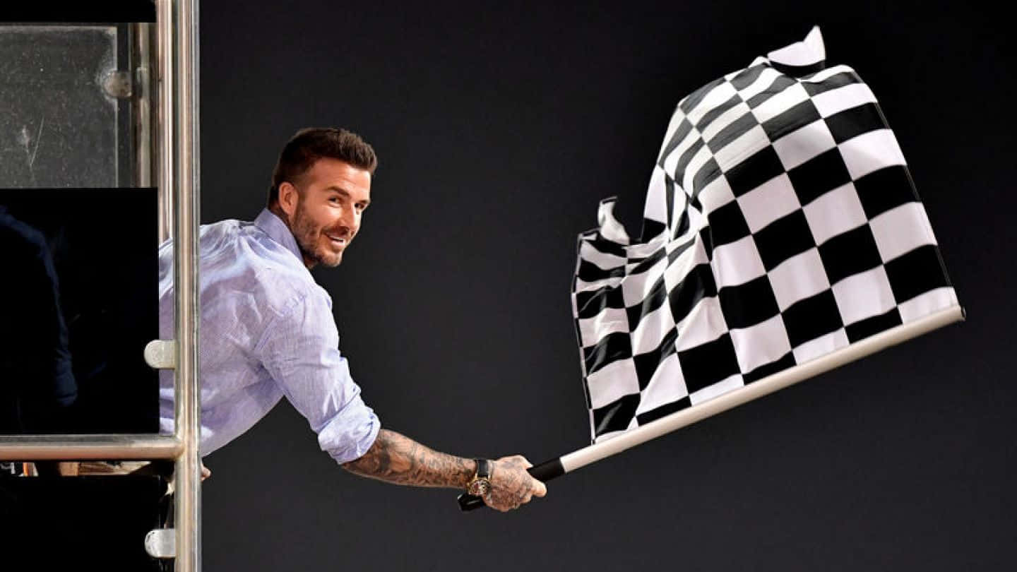 Chequered Flag 桌布 壁紙 — 大衛碧咸在黑暗背景的攤位中微笑揮動格仔賽車旗。