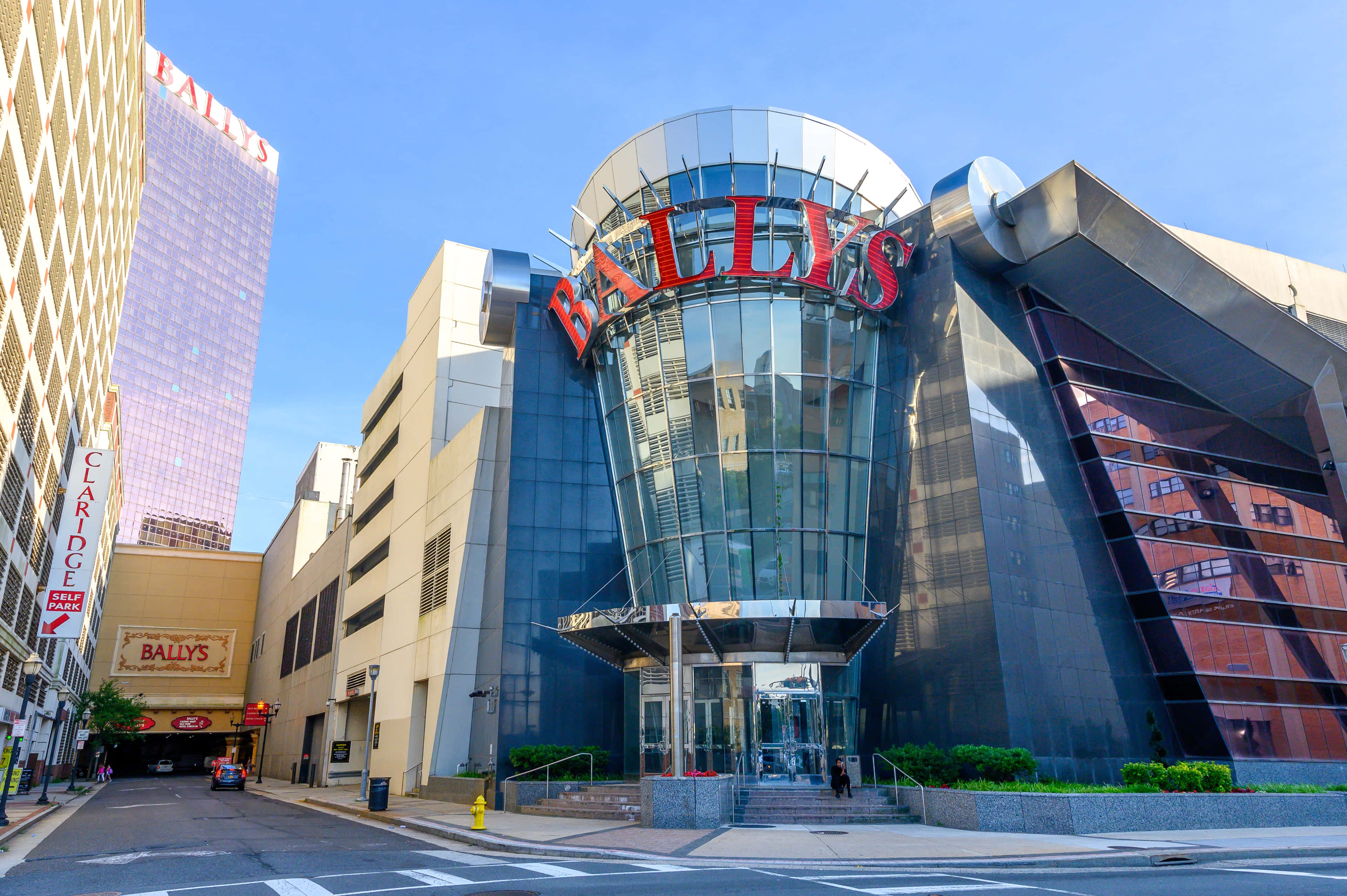 大西洋城巴利酒店與賭場 壁紙 — 現代玻璃和鋼結構的Bally's賭場建築，在晴朗藍天下帶有醒目的紅色標牌。