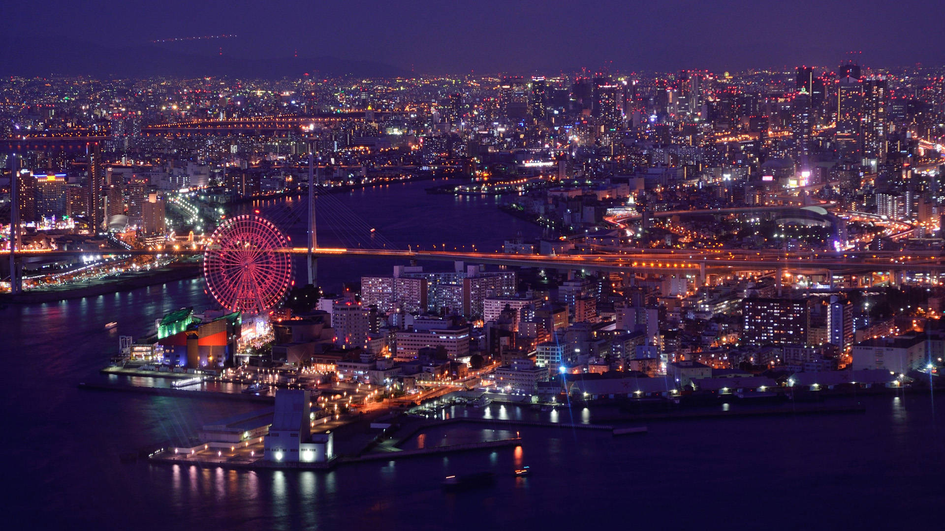 大阪灣夜景 壁紙 — 橫濱市景的夜間鳥瞰圖，帶有發光的摩天輪和照亮黑暗水面的橋樑。
