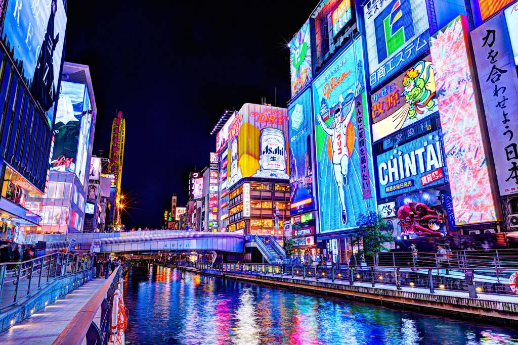 大阪道頓堀 壁紙 — 充滿活力的霓虹燈照亮了夜間繁忙的東京運河，在水面上反射出耀眼色彩。