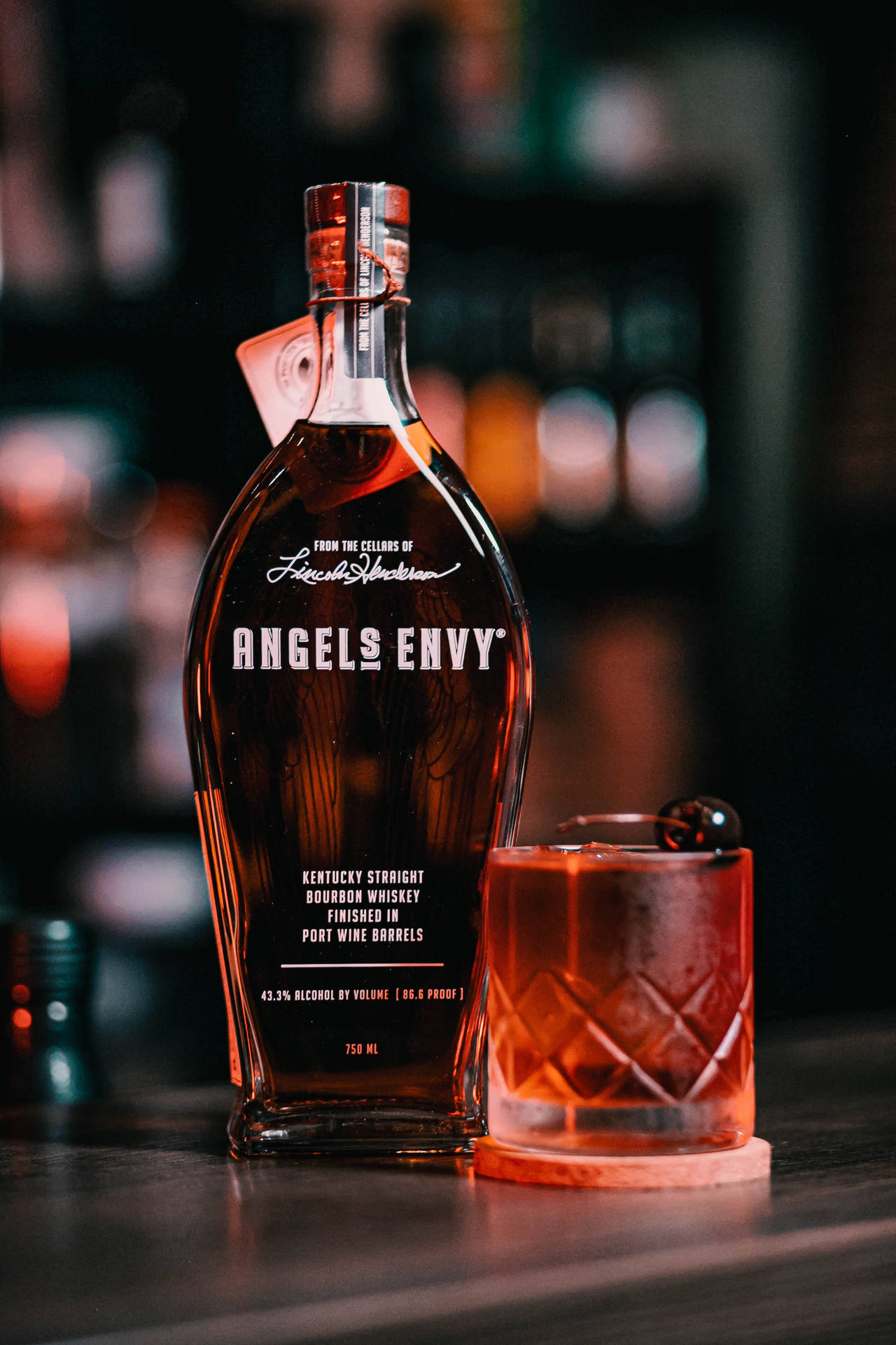 Angel's Envy波本威士忌瓶和帶櫻桃的雞尾酒在夜晚的酒吧