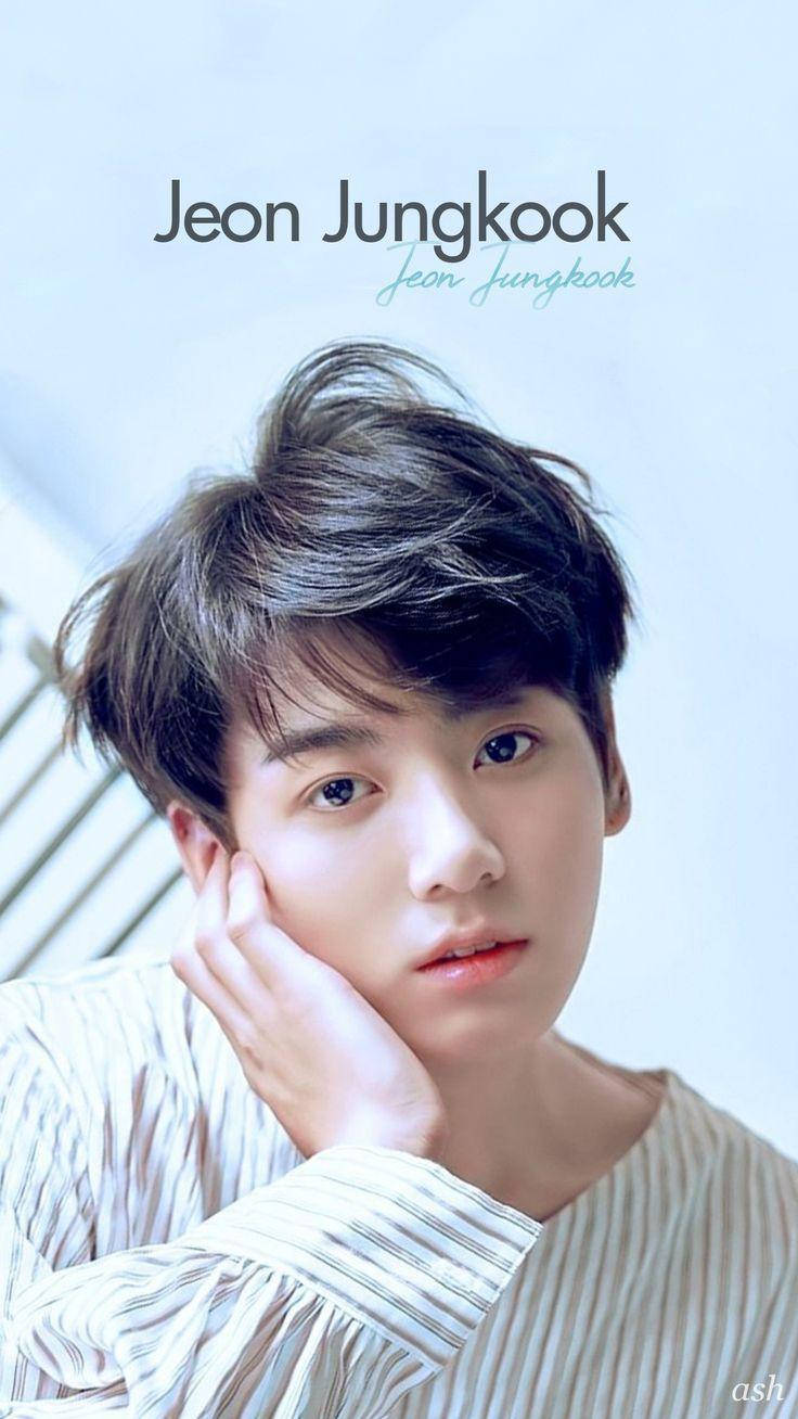 天使面容 Jungkook 美學壁紙 壁紙 — 一位年輕男子，一頭凌亂的黑髮，在柔和的藍色背景前用手托著下巴。