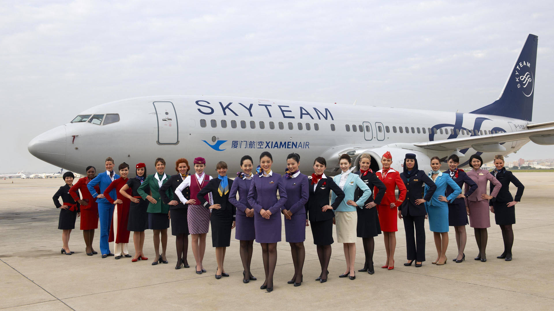 一群穿著色彩繽紛制服的航空公司員工在飛機前擺姿勢。