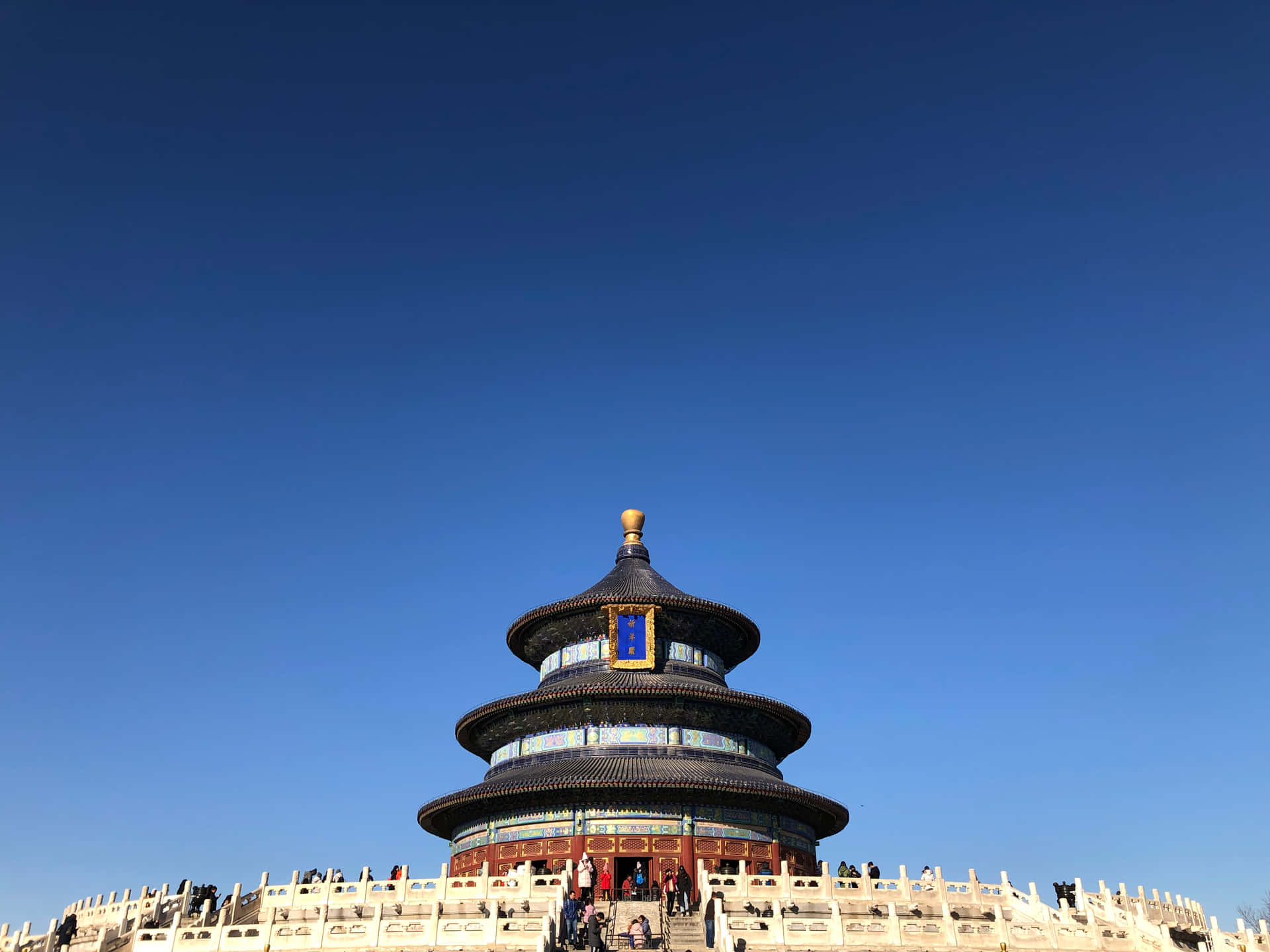 天壇上空澄澈的藍天 壁紙 — 宏偉的天壇，分層藍色屋頂，在晴朗藍天下巍然聳立，遊客在石欄杆上。