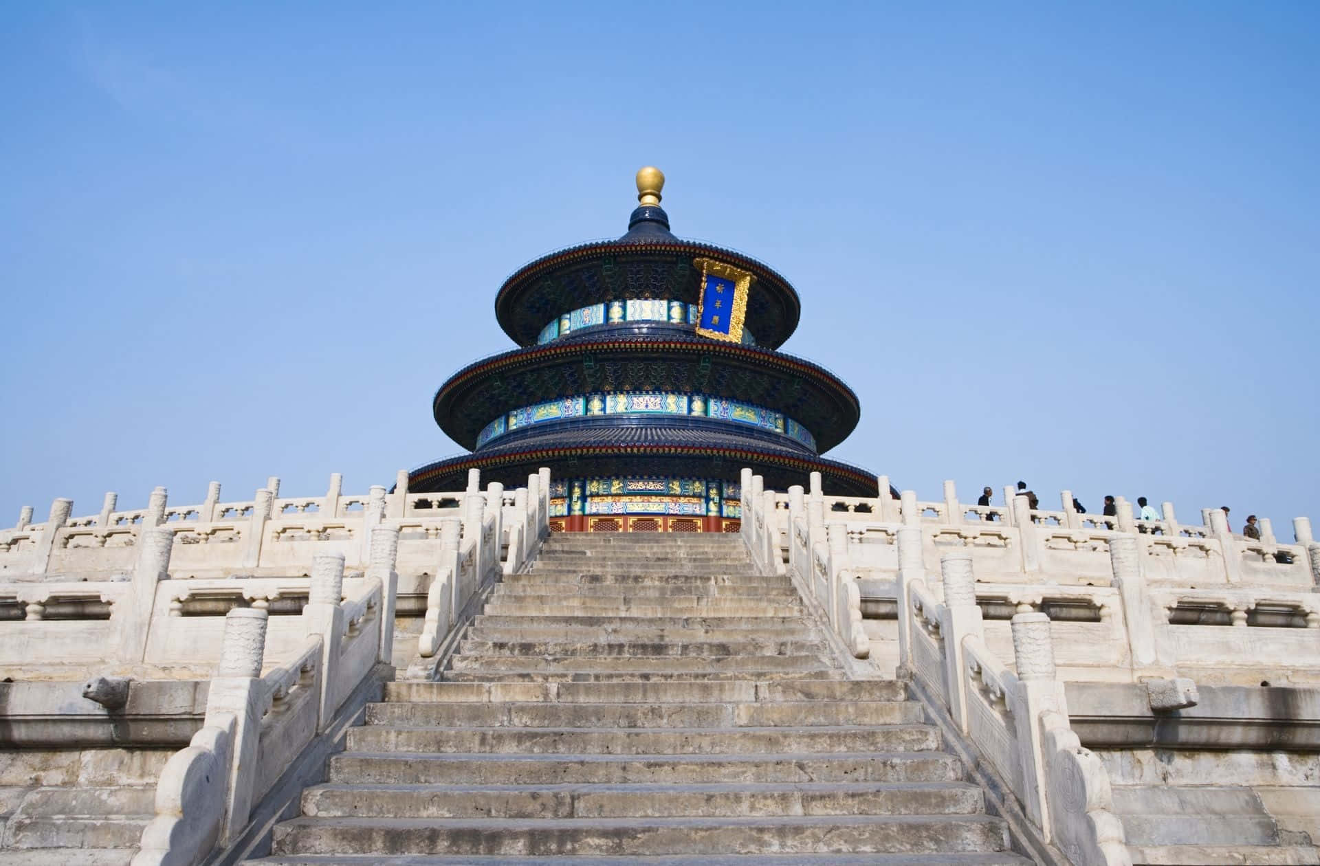 天壇主殿的陡峭步道 壁紙 — 宏偉的分層寺廟，藍色瓦片屋頂和金色尖頂，在晴朗的藍天下矗立在寬闊的石階之上。