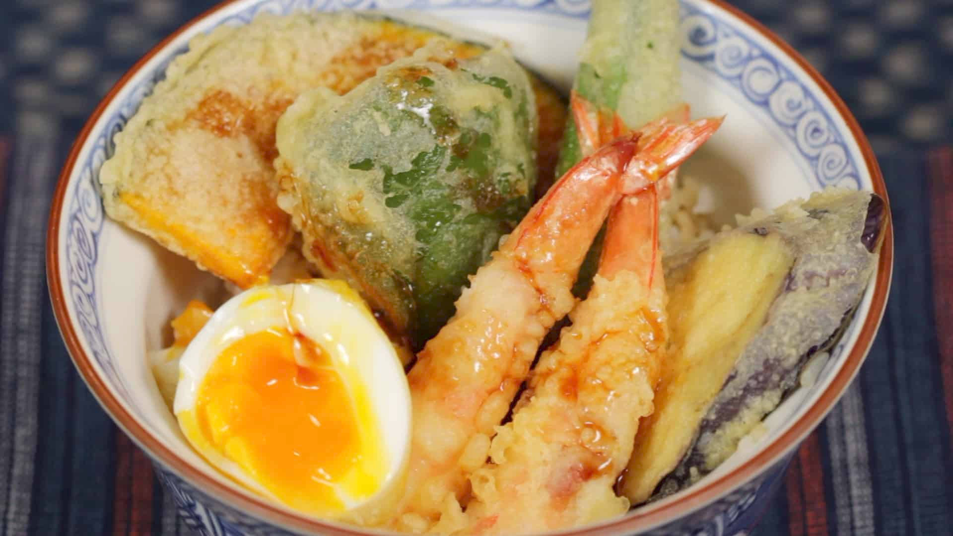 天婦羅配蛋 壁紙 — 一碗熱騰騰的天婦羅特寫，包括蝦、茄子和蔬菜，配上溏心蛋並淋上醬汁。