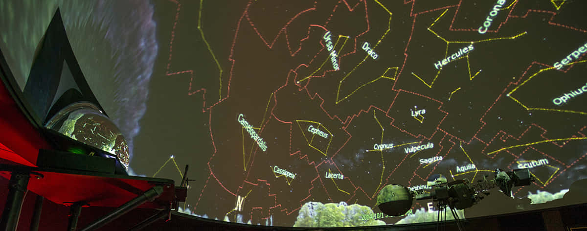 Planetarium 桌布 壁紙 — 天文館圓頂在黑暗的星空背景下顯示發光的黃色星座線條和名稱，前景有一個紅色望遠鏡。