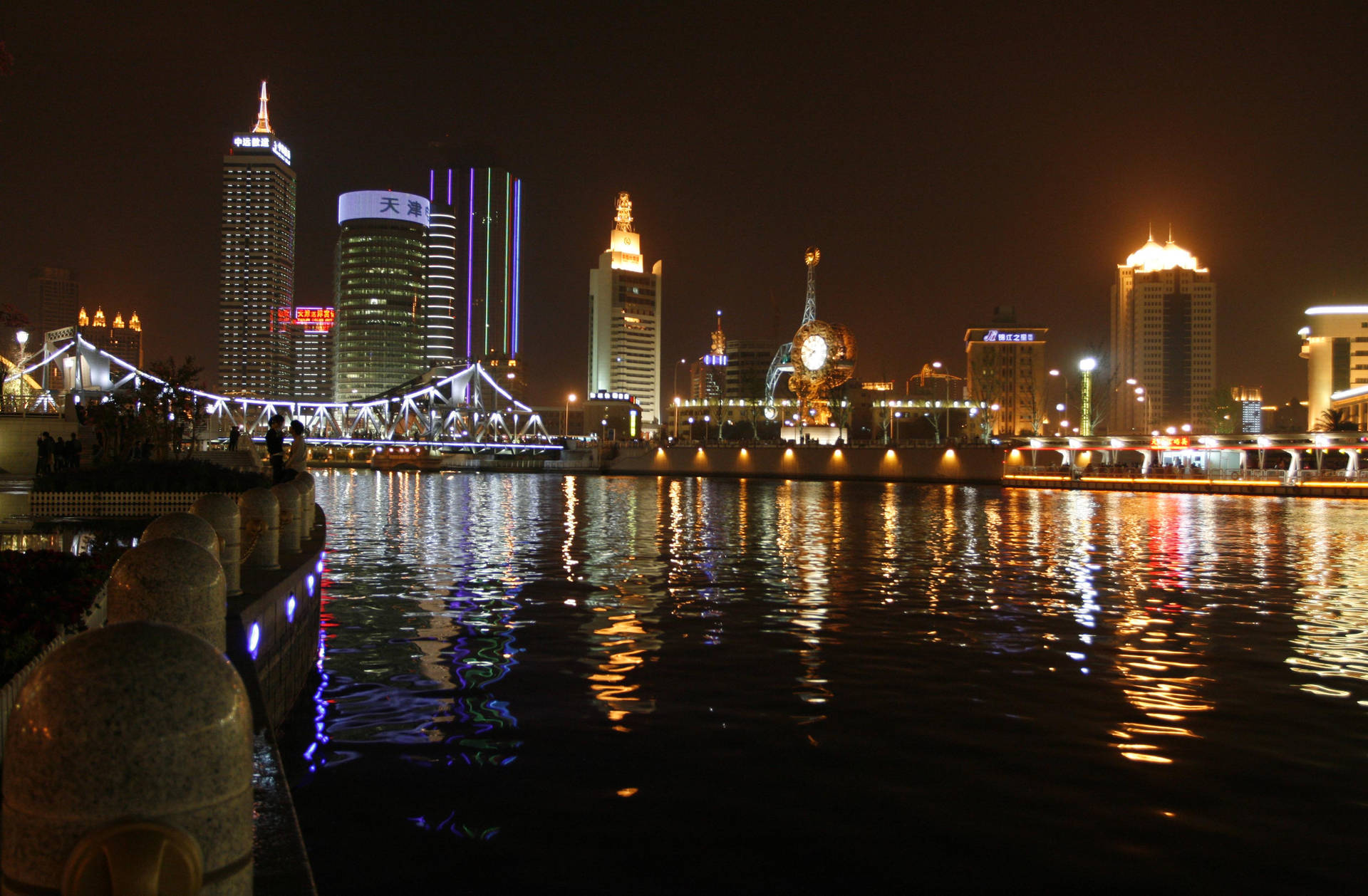 城市天際線的夜景，有明亮的建築物和水上的橋樑。