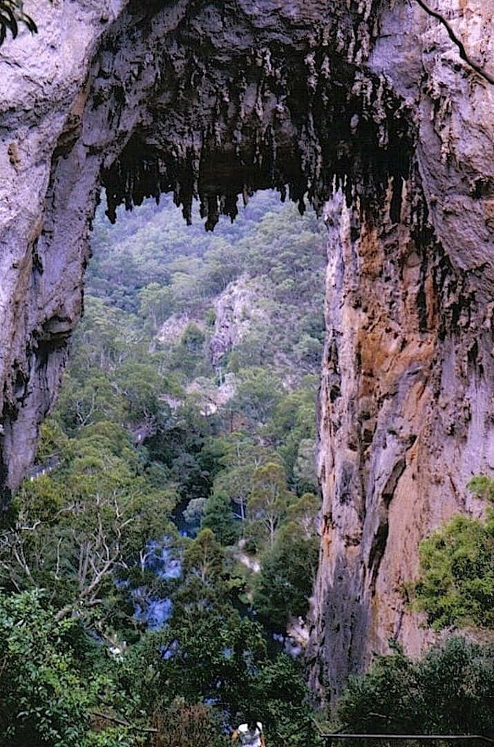 Blue Mountains National Park 桌布 壁紙 — 天然岩石拱門框住下方有蜿蜒河流的翠綠山谷。