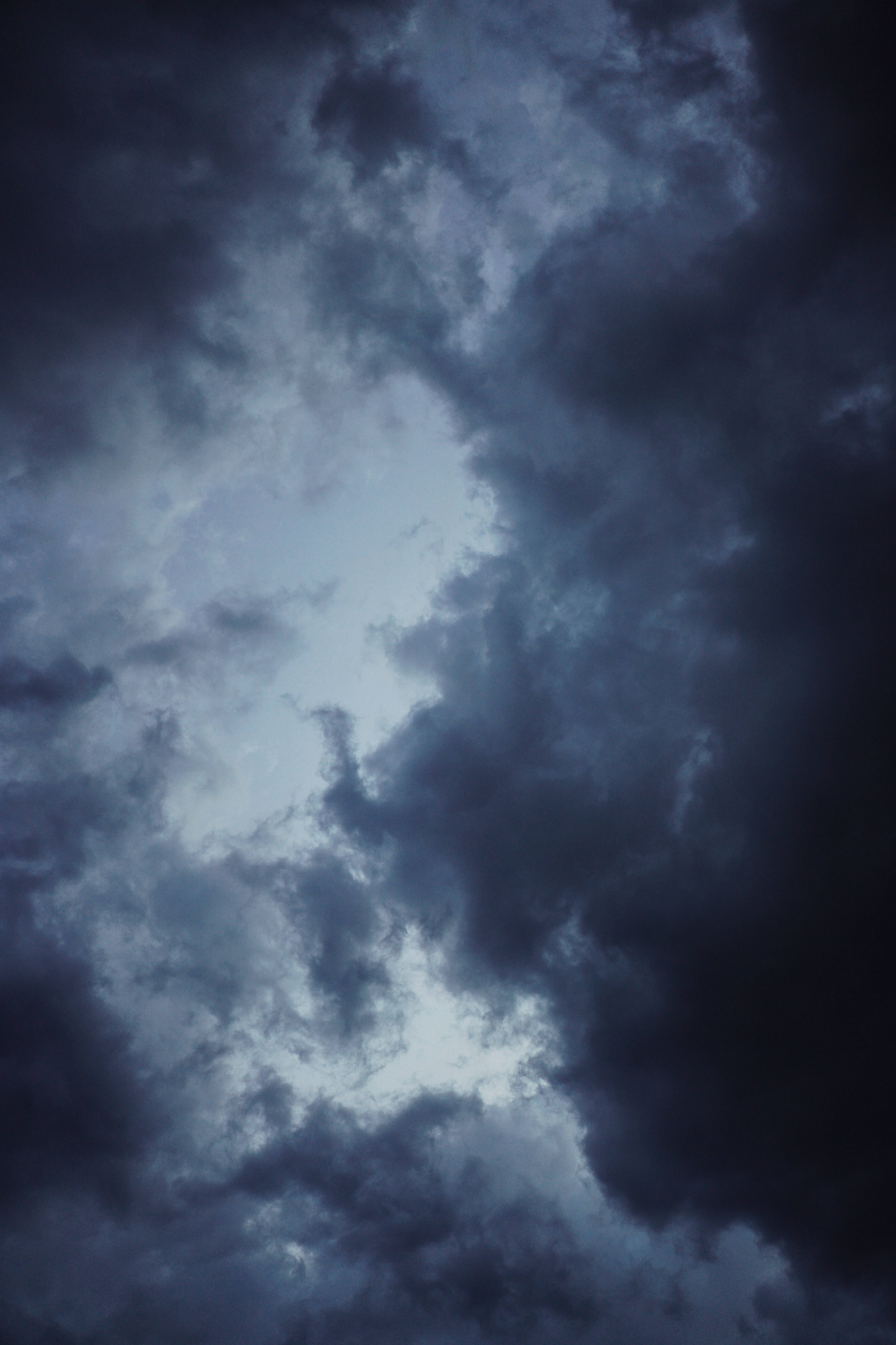 天空中的暴風雲 壁紙 — 戲劇性的烏雲在陰鬱的黃昏天空中旋轉，夾雜著淡藍色光線穿透而出。