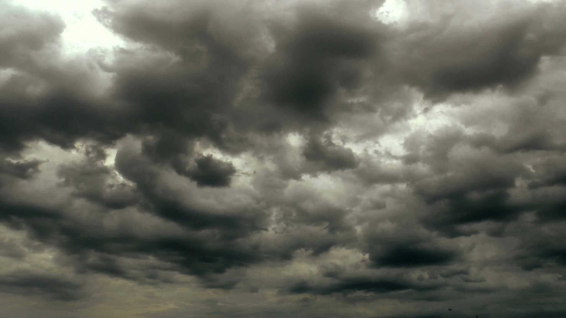 陰沉灰色天空中帶有明亮斑塊的戲劇性黑暗風暴雲。