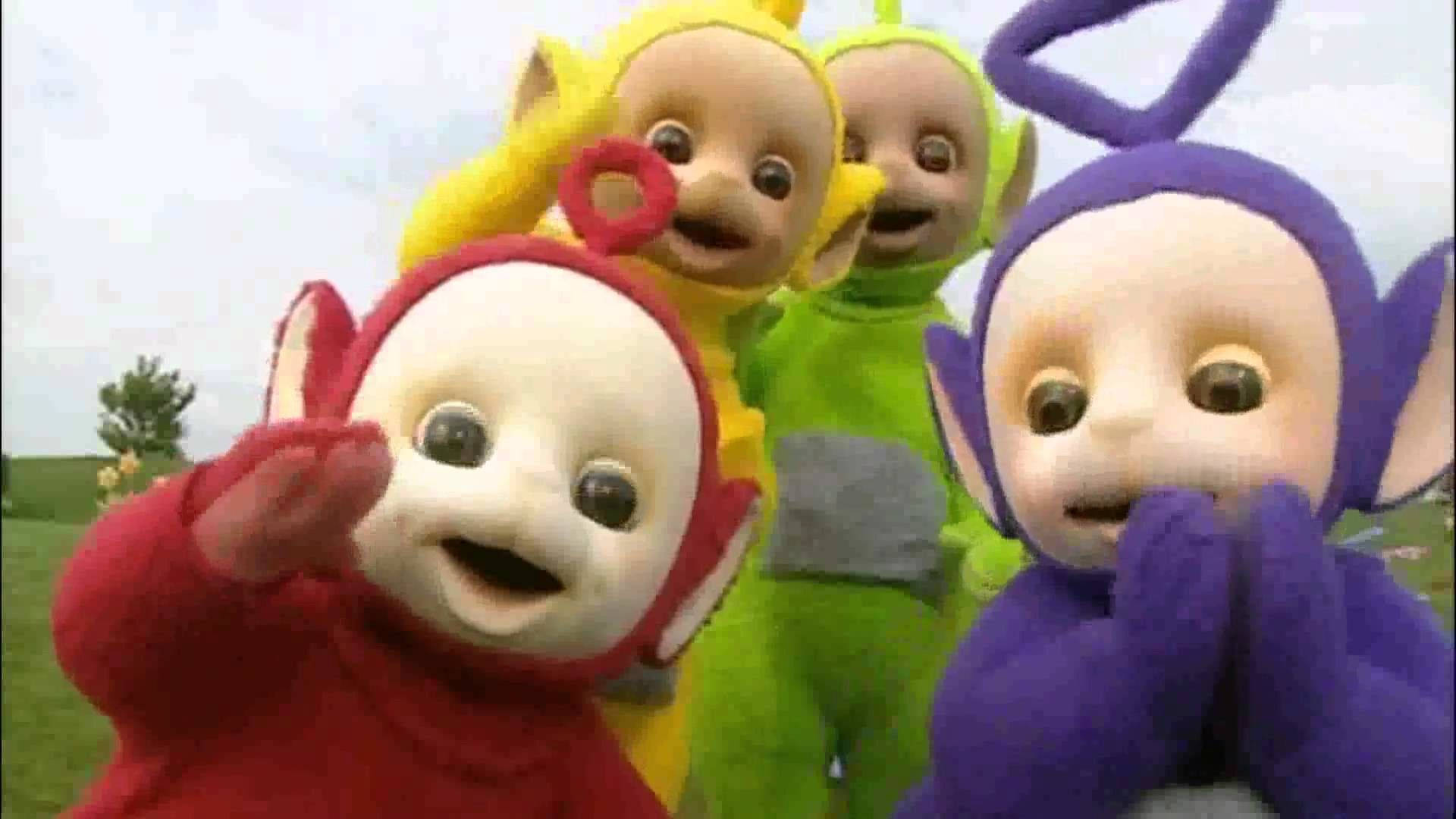 四個色彩繽紛的卡通人物在草地上揮手微笑。