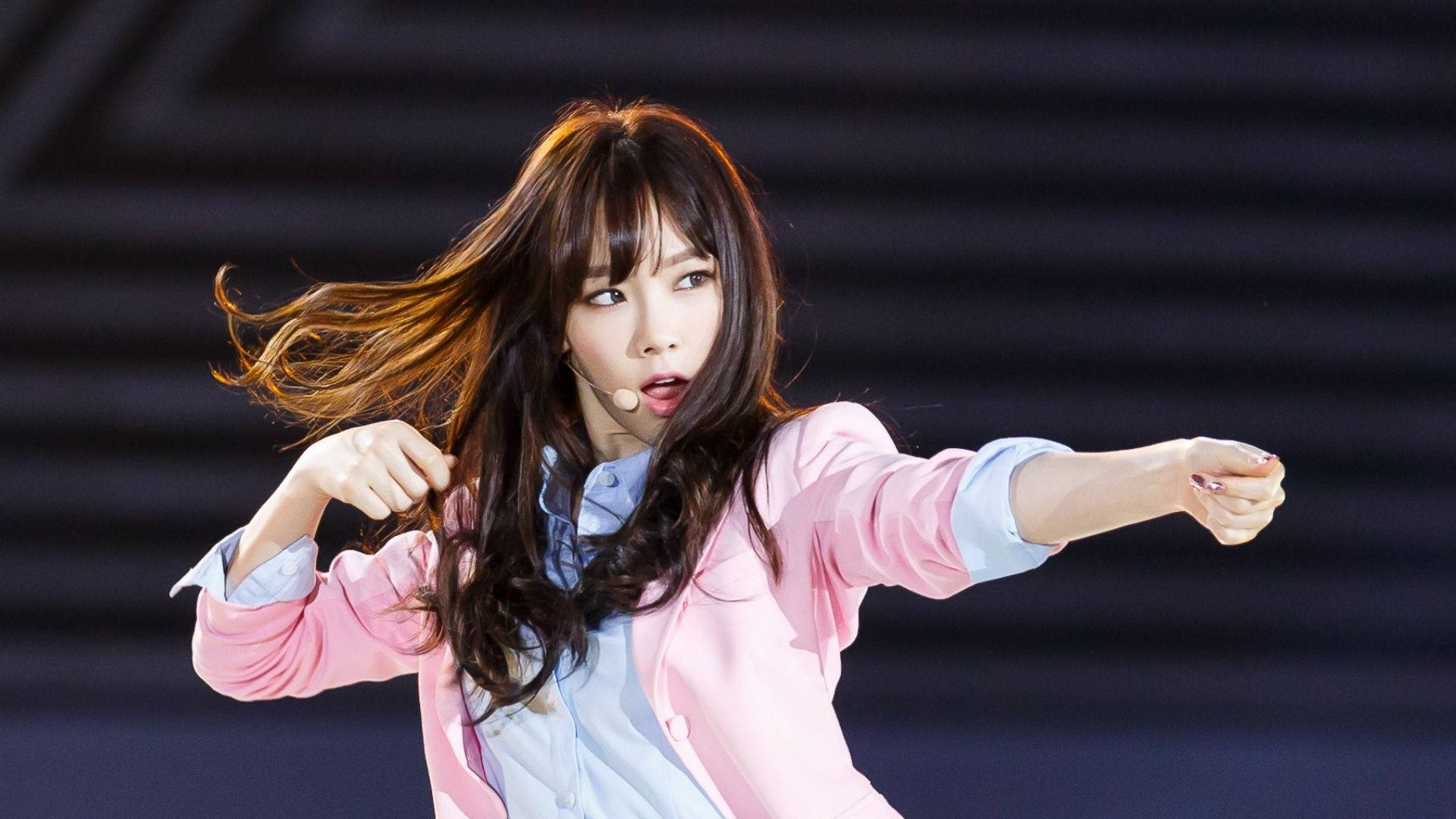 太妍粉紅外套舞台表演 壁紙 — 一位擁有飄逸棕色長髮的女表演者在舞台燈光下穿著粉紅色西裝外套動感起舞。