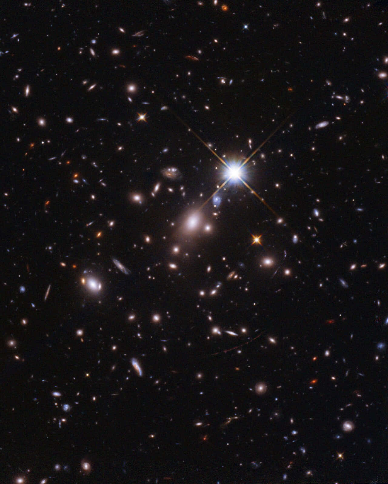 太空中的星群天文 壁紙 — 一個充滿遙遠星系和一顆帶有衍射尖刺的燦爛恆星在黑色虛空中發光的宇宙景觀。