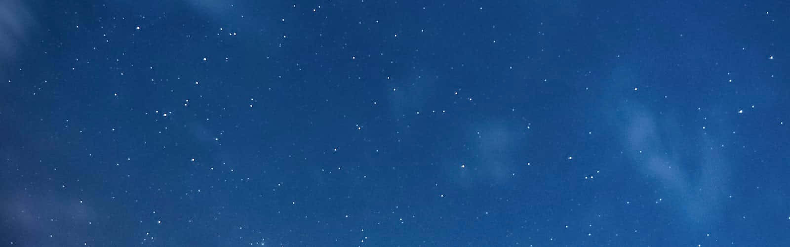 太空中的星雲與星辰 壁紙 — 廣闊深藍夜空，佈滿閃爍繁星與輕柔縷縷雲彩飄過天際。
