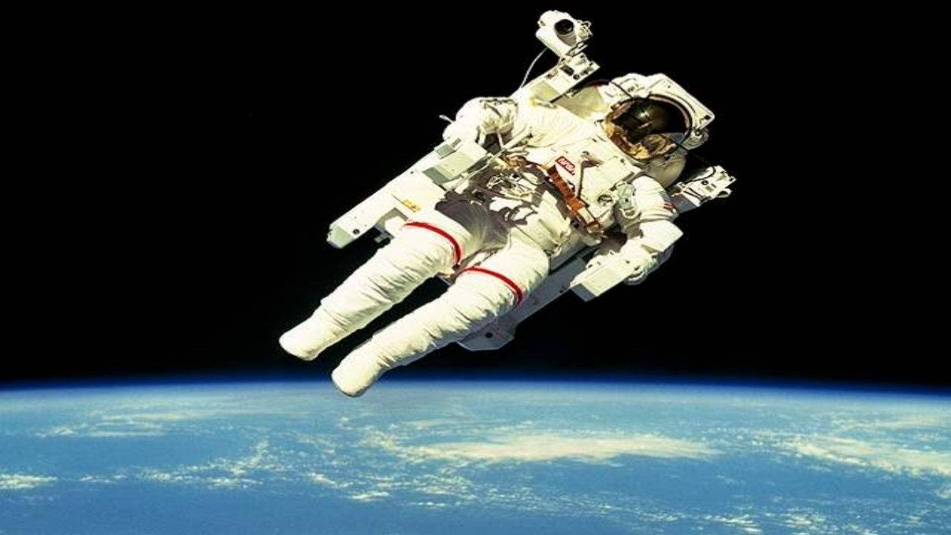 穿著太空衣的太空人漂浮在地球藍色曲線之上。