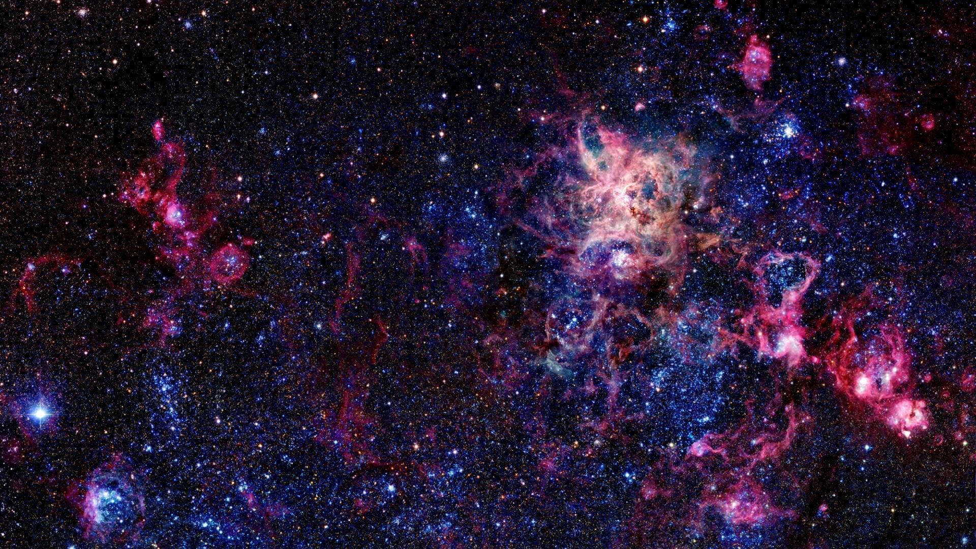 在深空中無數恆星之間發光的充滿活力的粉紅色和藍色星雲雲團。