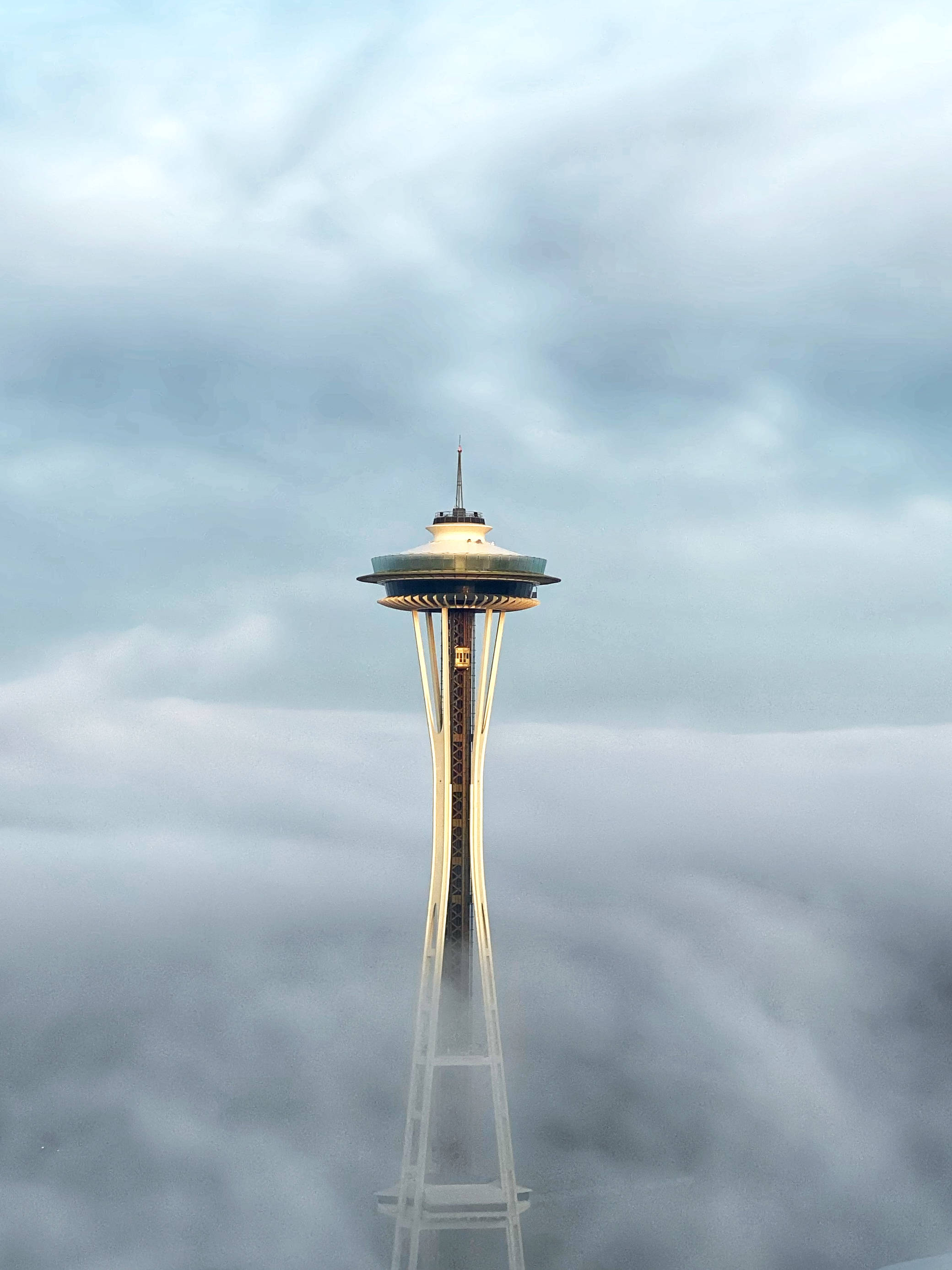 Space Needle In Seattle iPhone 壁紙 — 太空針塔在陰沉灰暗的天空下，穿透厚厚的雲層。